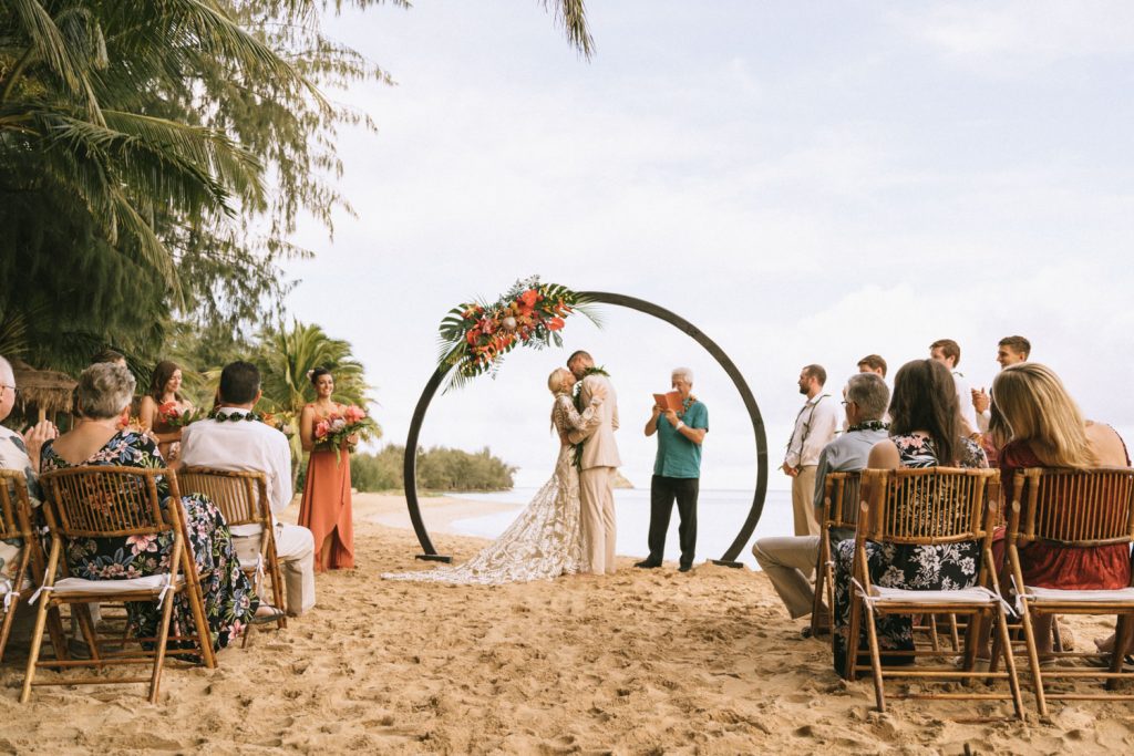 couple stands under round arch at secret island at kualoa ranch wedding venue