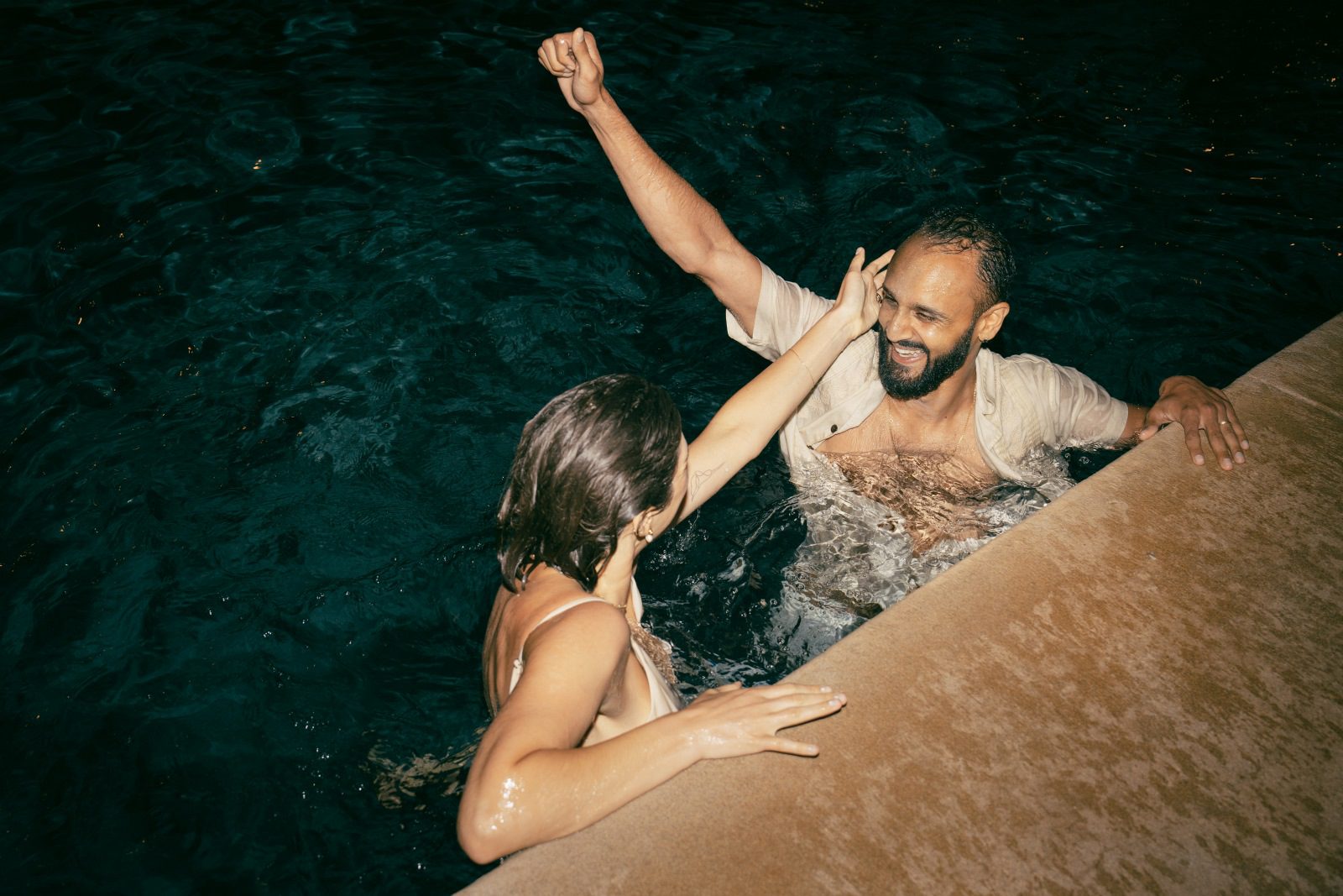 Newlywed couple jumps in the pool after their ceremony.