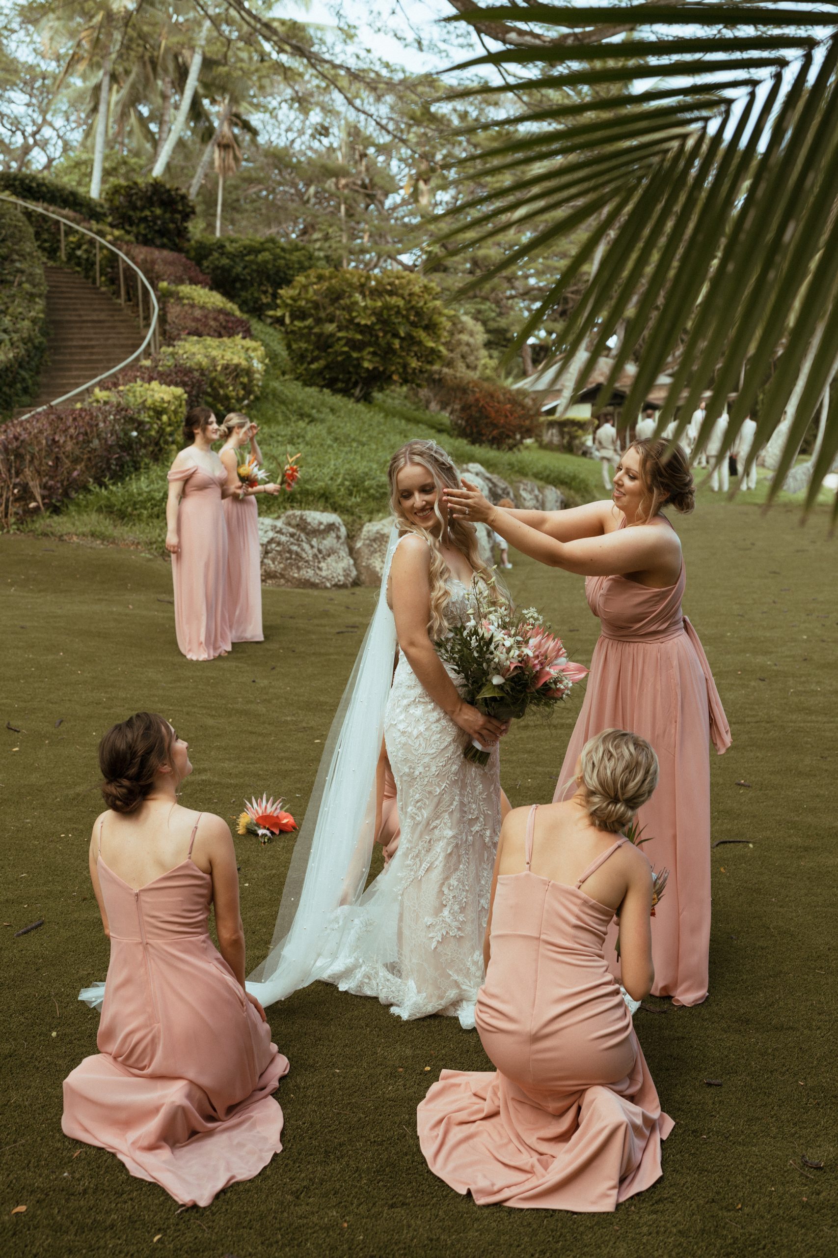 Hawaii wedding videographer captures bridal party helping bride with dress.