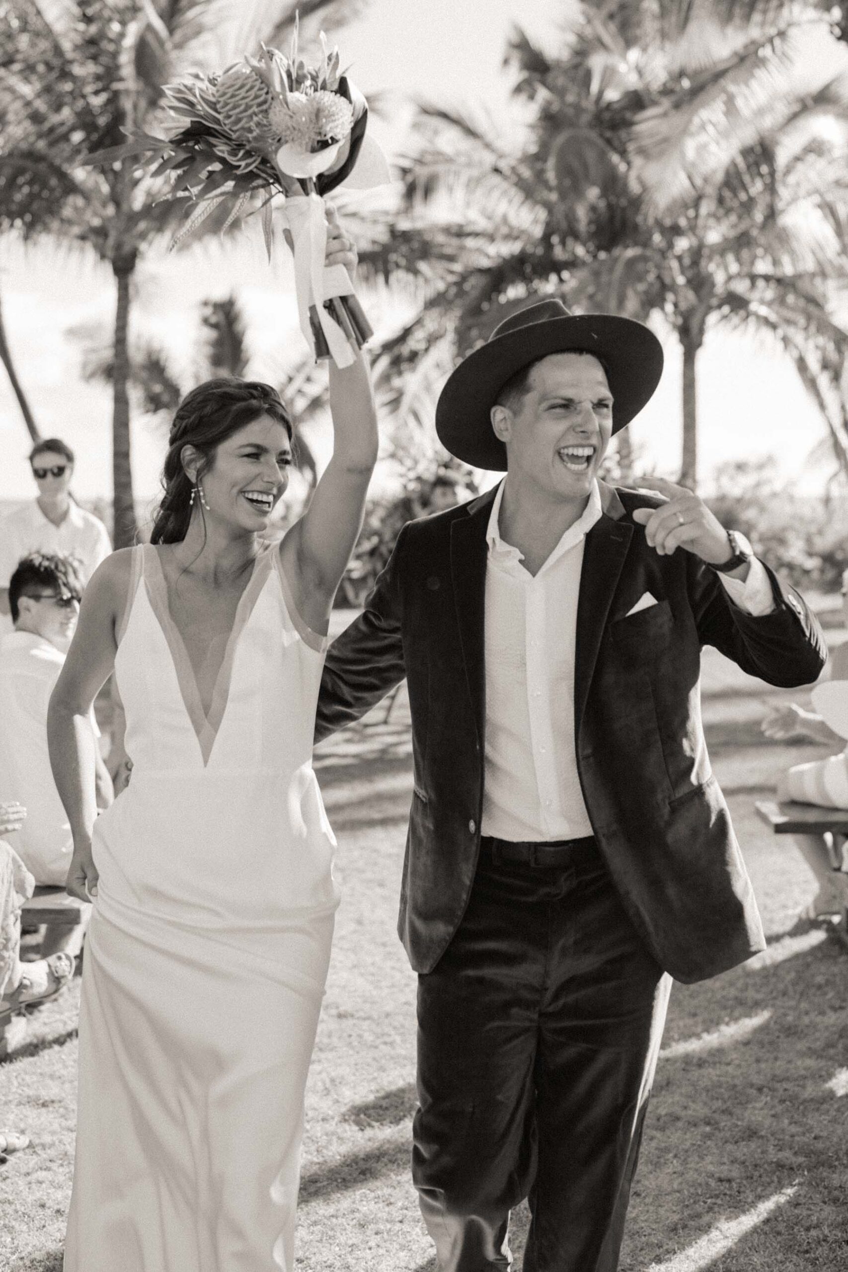 Black and white photo of couple leaving ceremony and are excited.