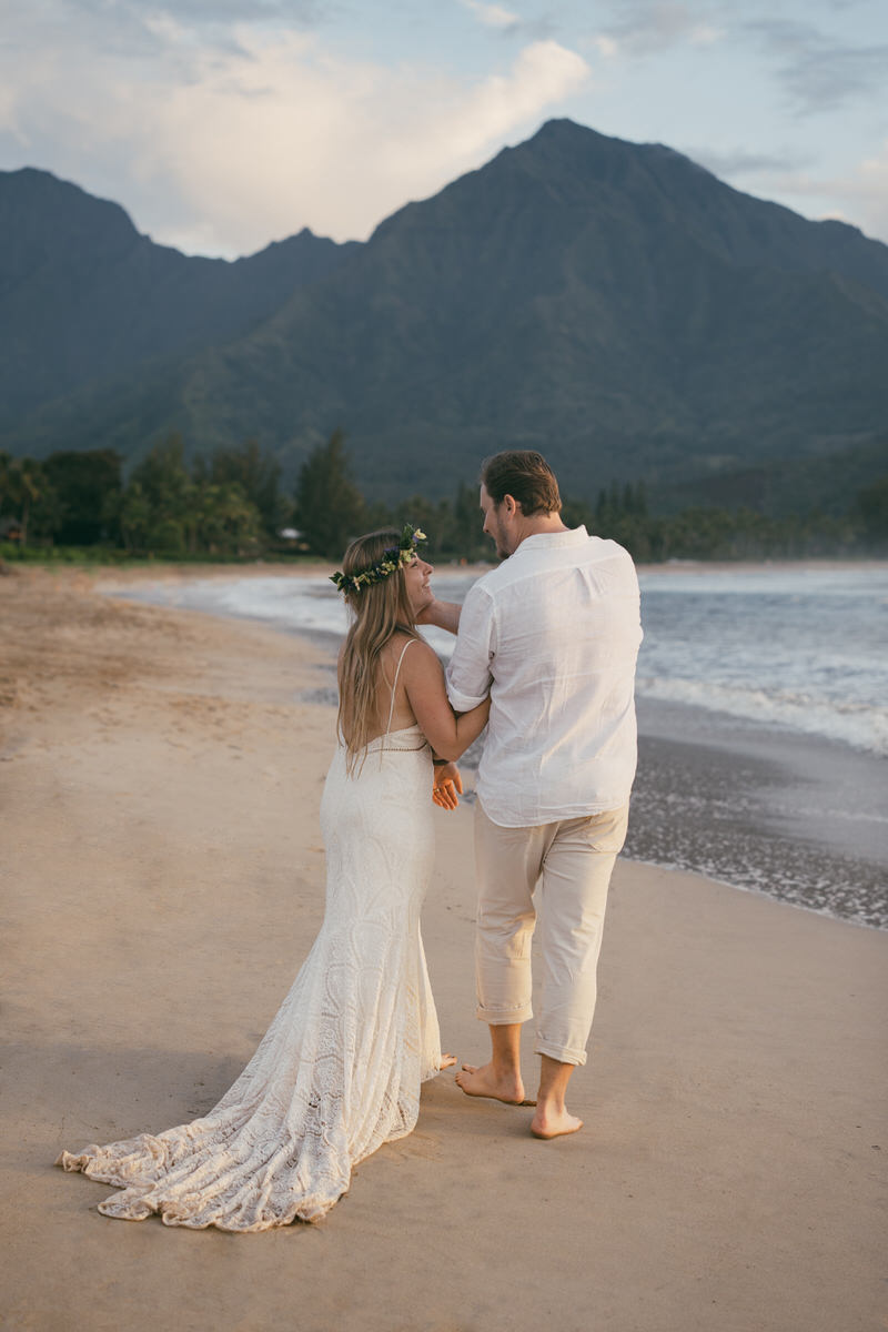 Bride and groom walking along beach in Hanalei.