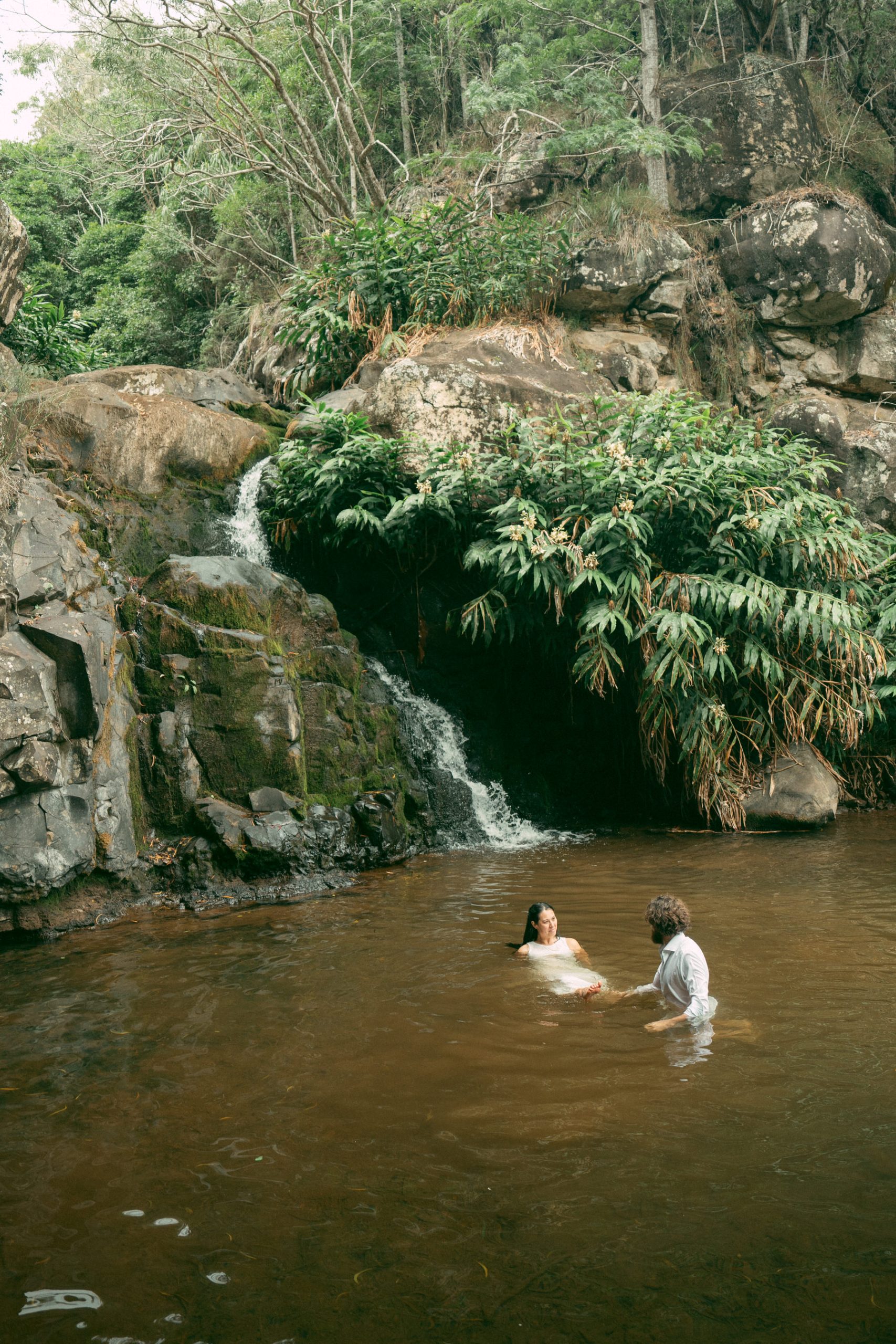 Newlyweds jump in a waterfall during their Kauai elopement.