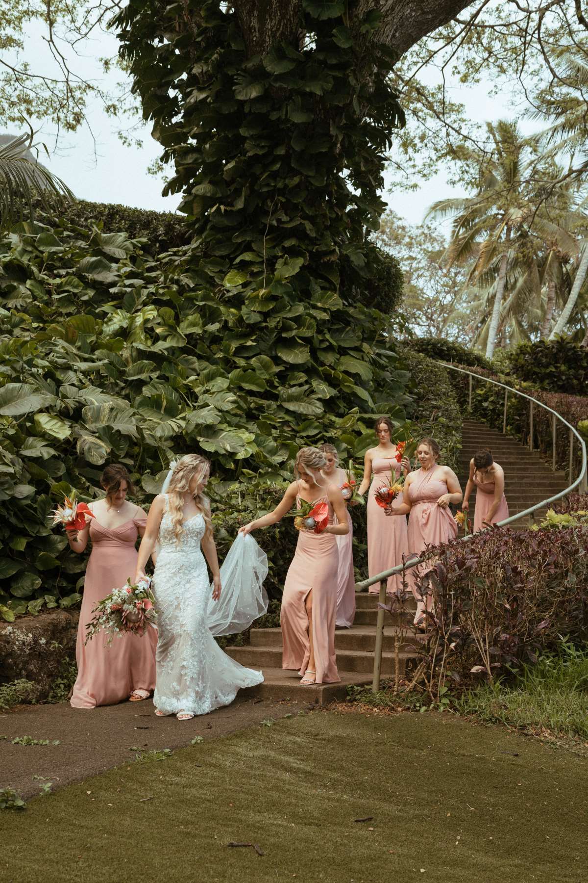 Bridesmaids helping bride with dress at Moili'i Gardens at Kualoa Ranch.