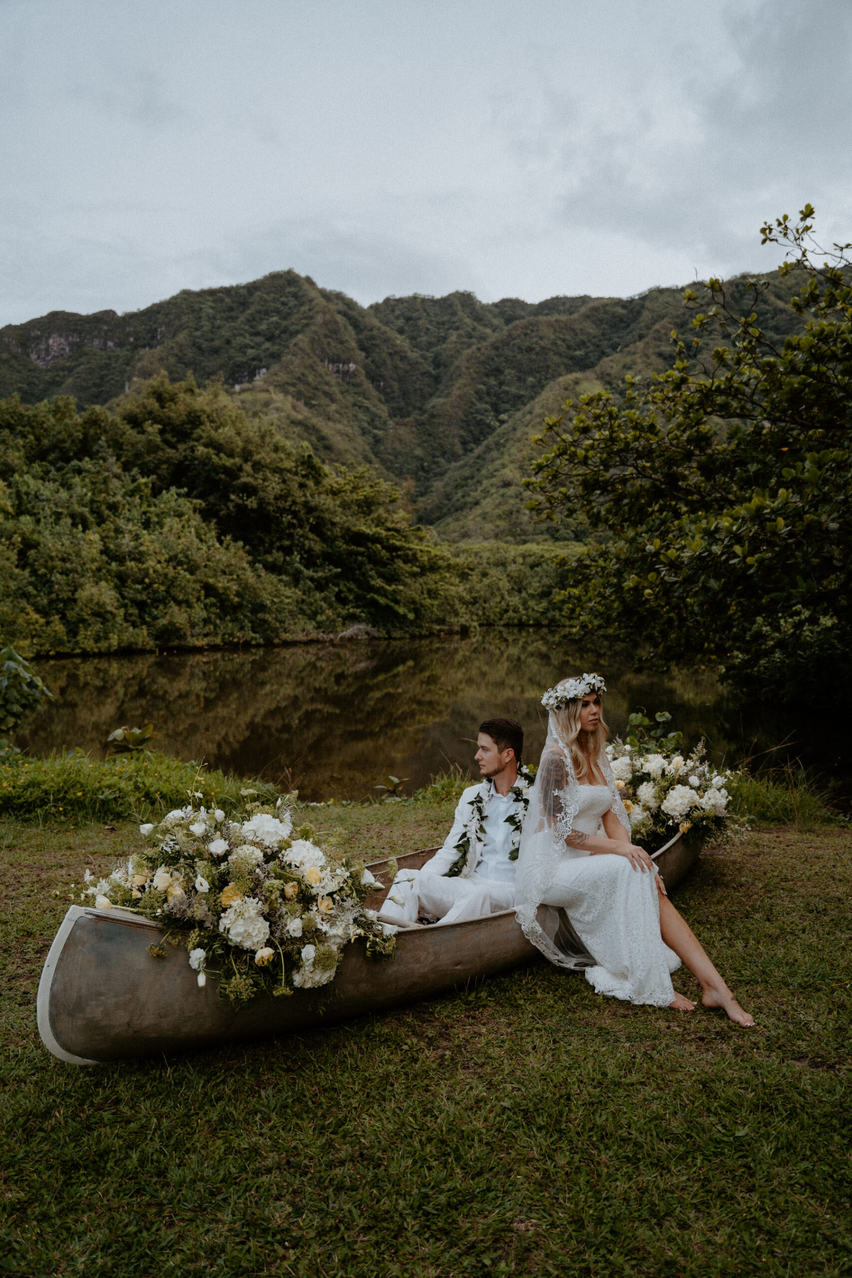 Bride and groom pose in floral filled canoe.