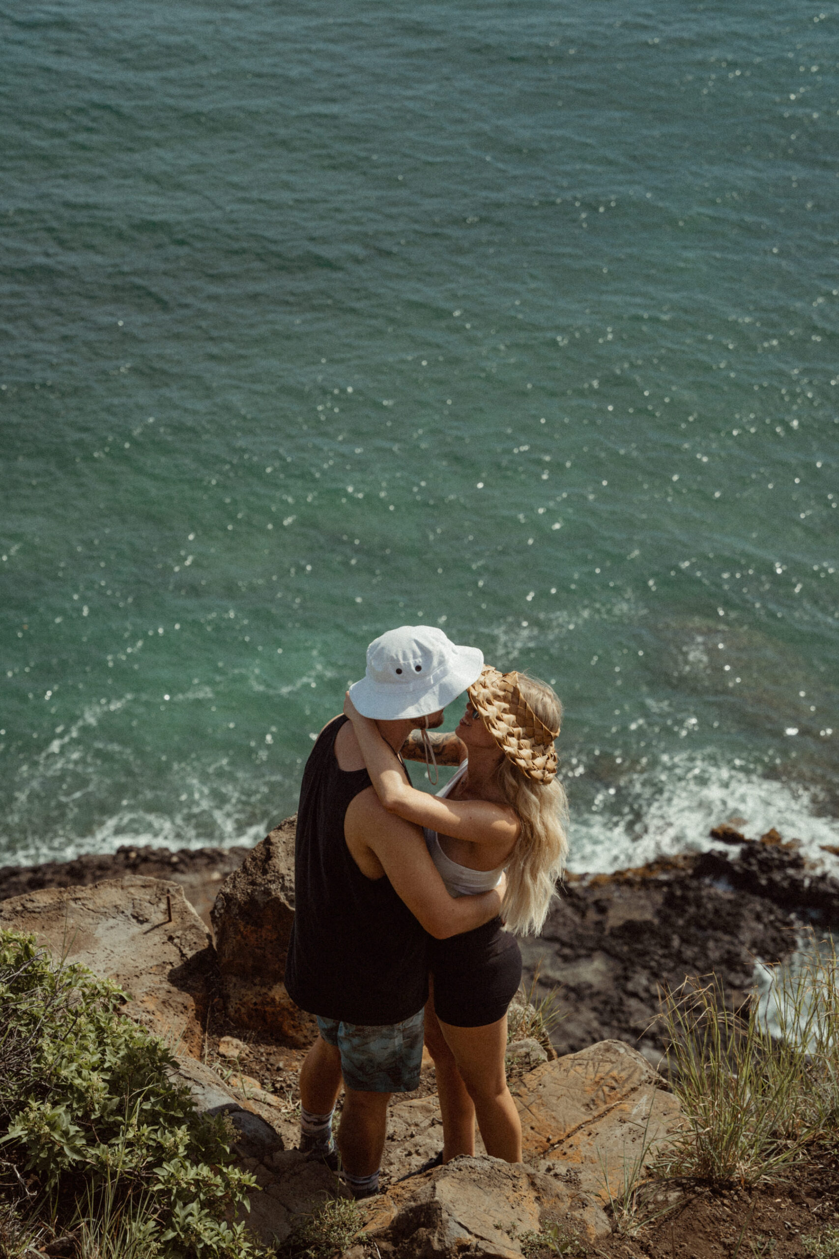 A young couple shares an embrace with the ocean in the background.