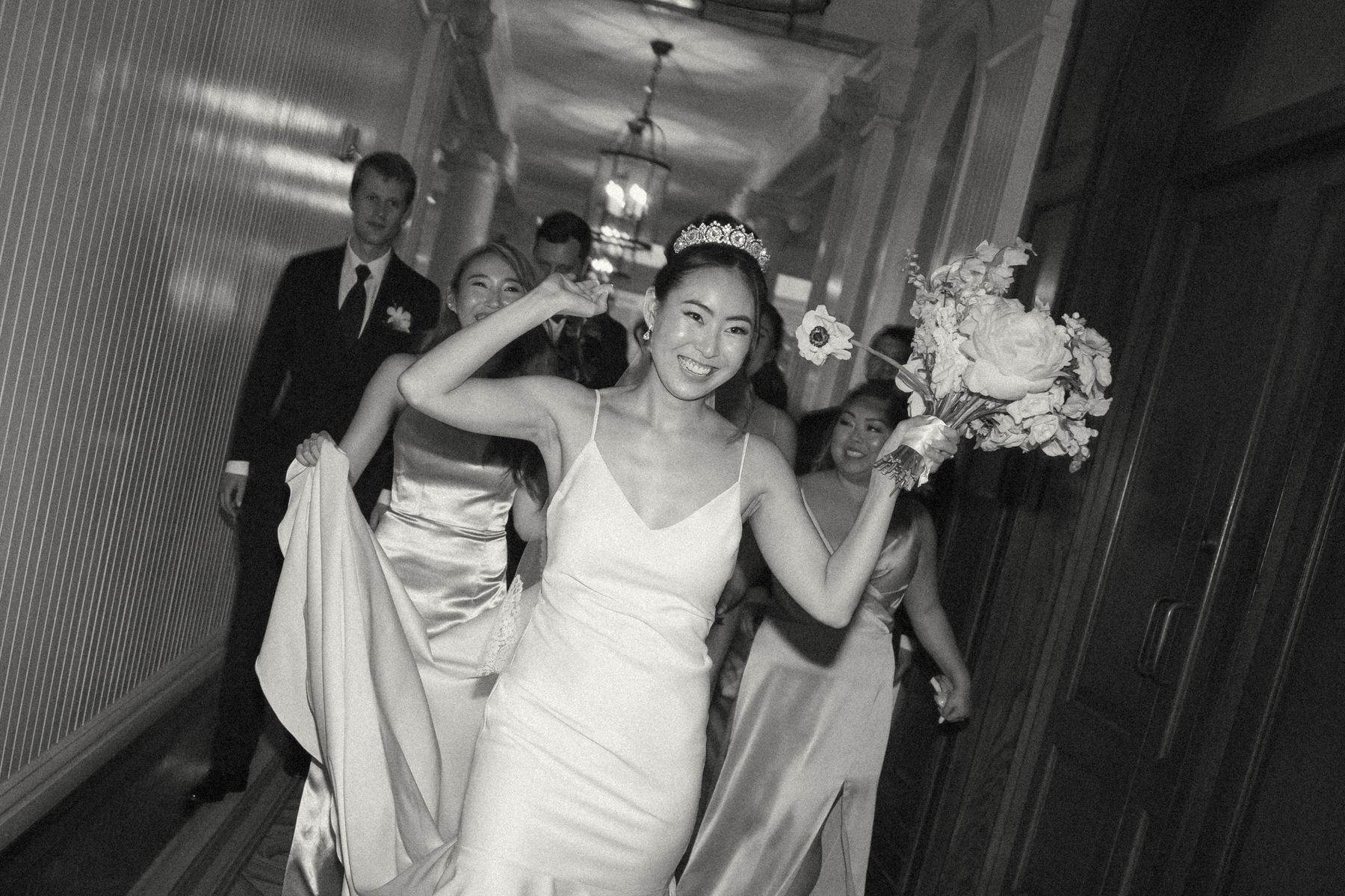 Black and white image of bride followed by her wedding party.