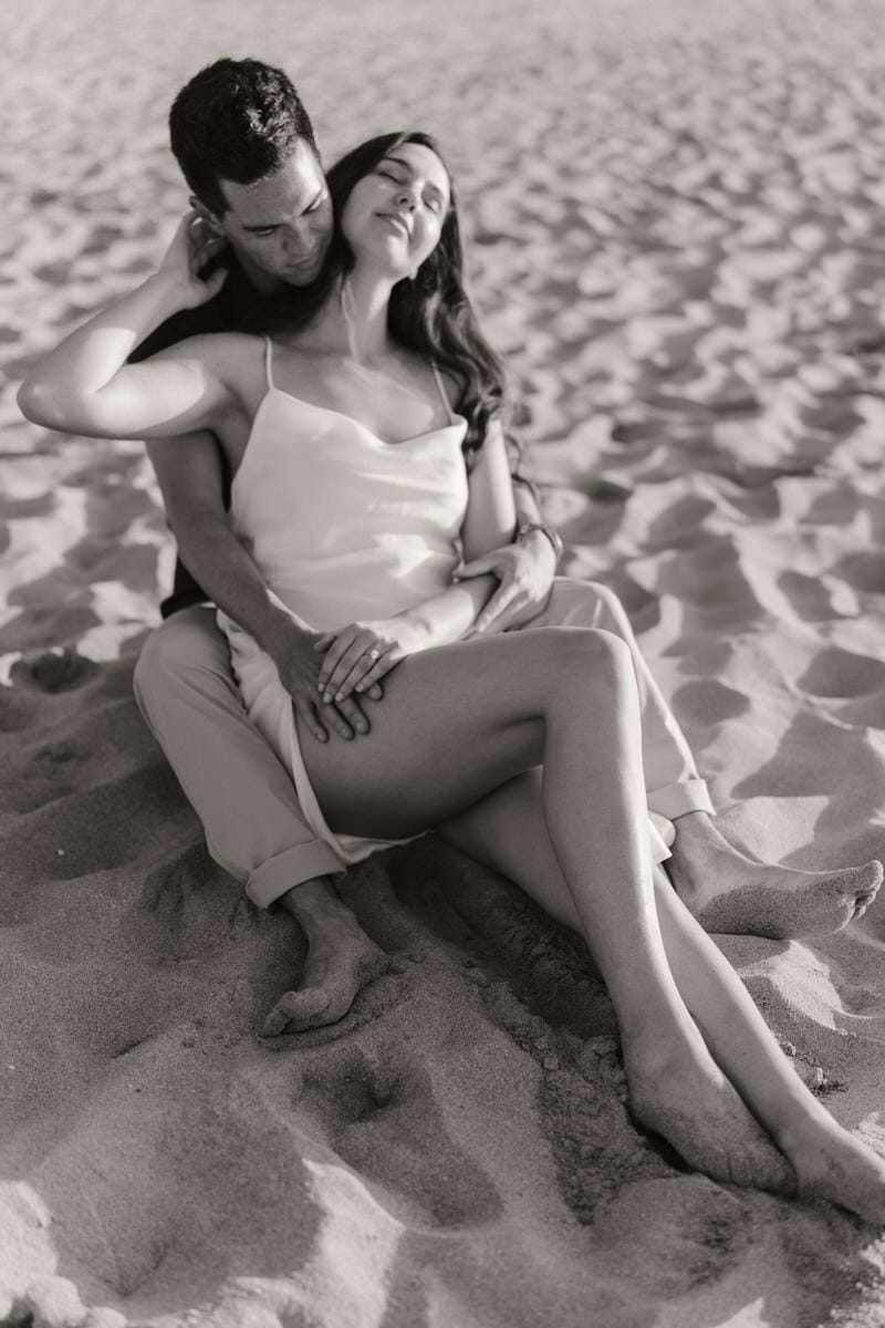 a man and woman sitting on sand