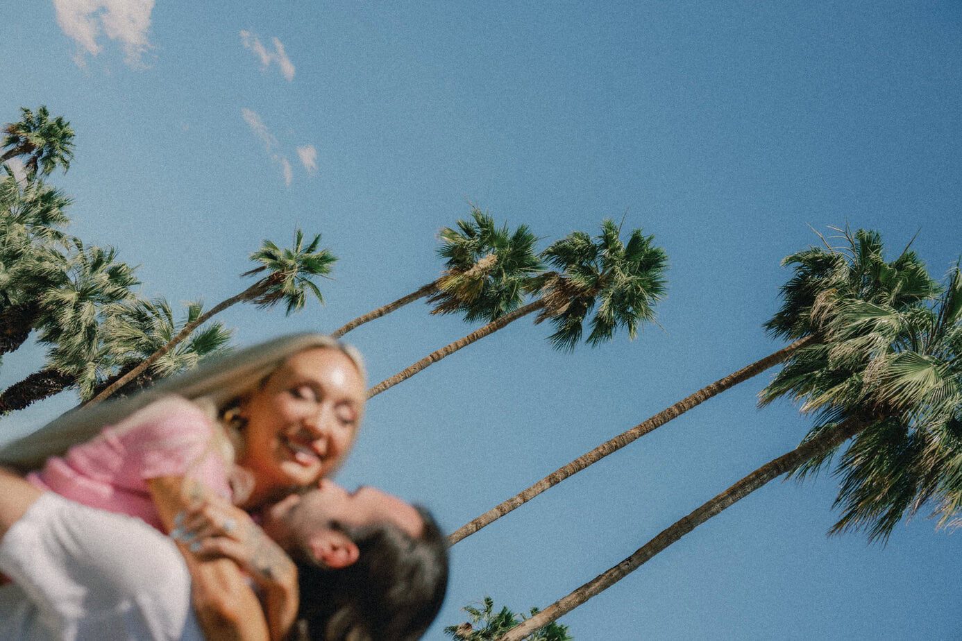 Couple embraces with Palm Trees in the back.