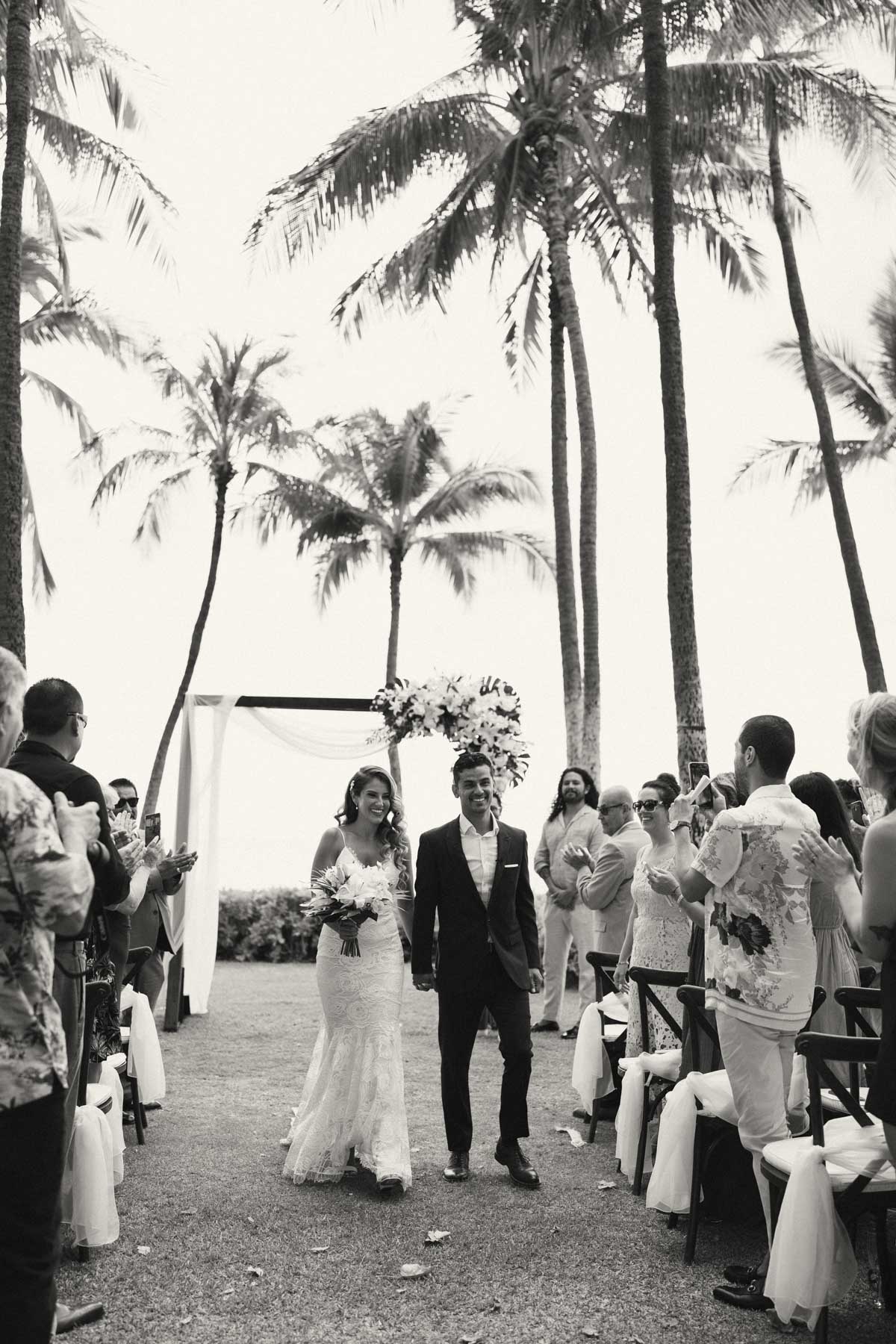 A black and white photo of bride and groom leaving ceremony at Lanikuhonua Cultural Institute.