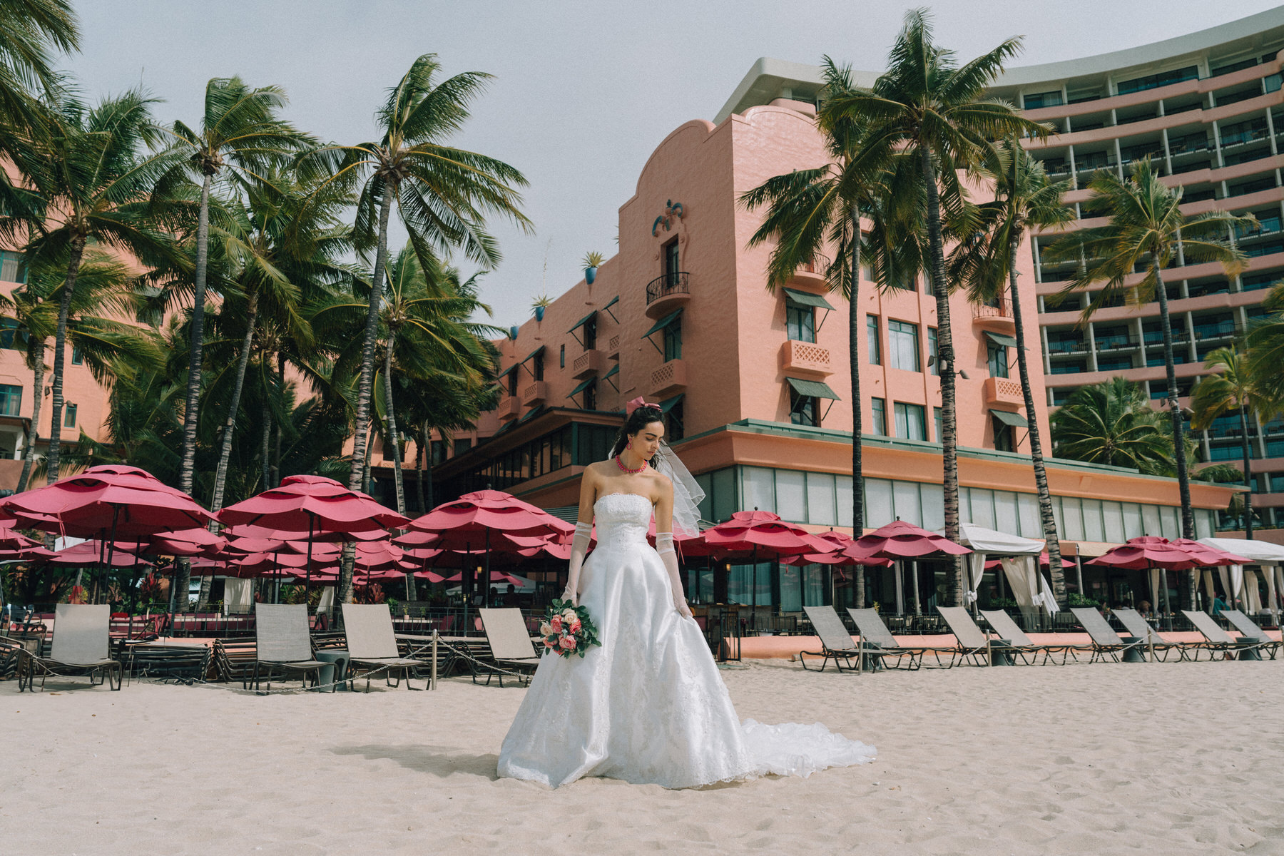 A bride poses in front of the iconic Royal Hawaiian Hotel, one of the best Oahu wedding venues.