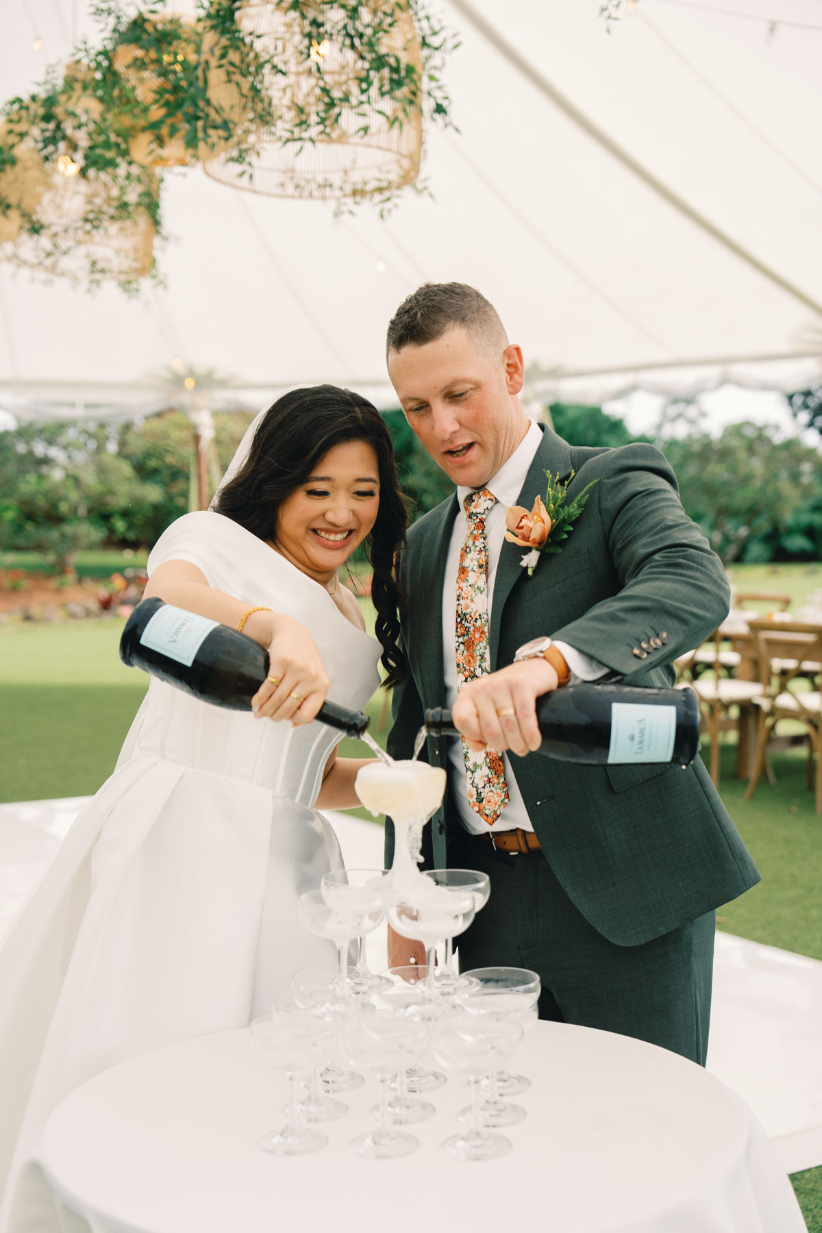 Bride and groom pour a champagne tower at a wedding at Sunset Ranch Oahu.