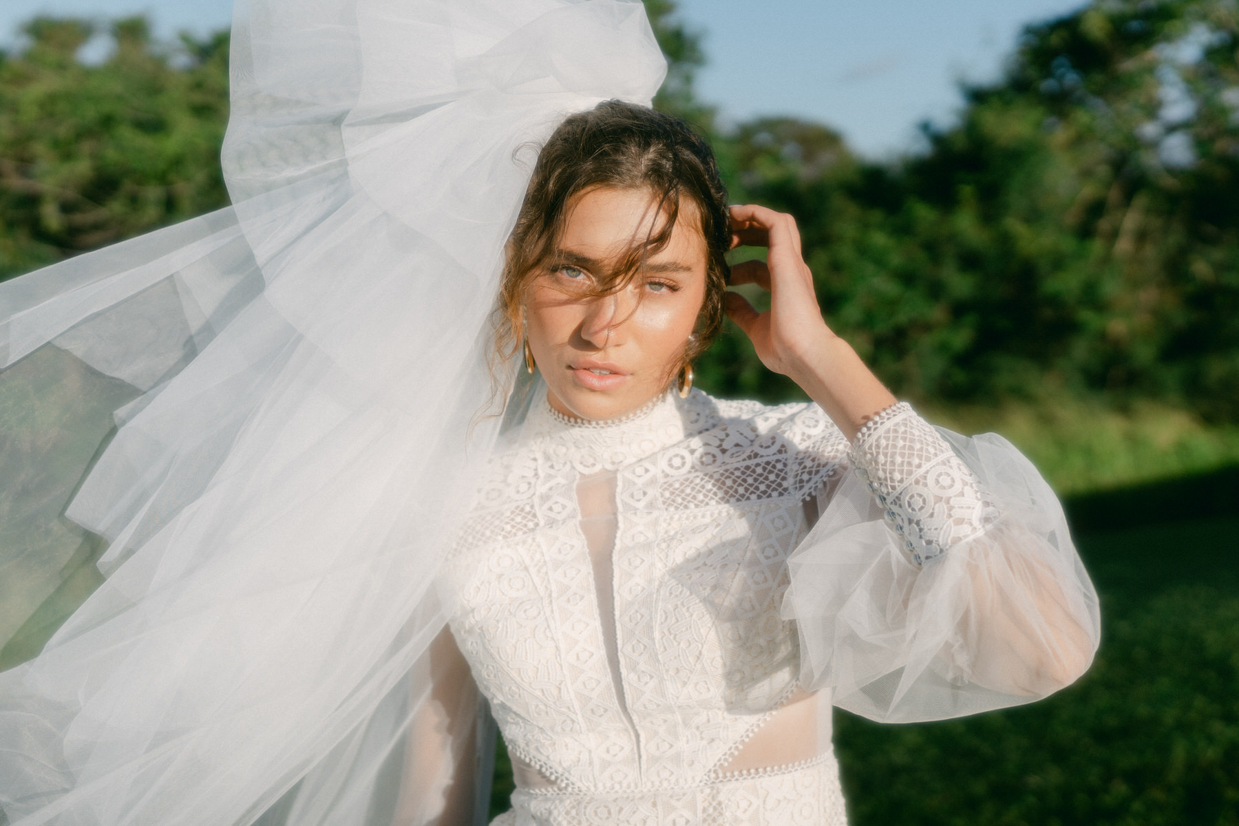 Portrait of bride getting hair out of face as the wind blows.