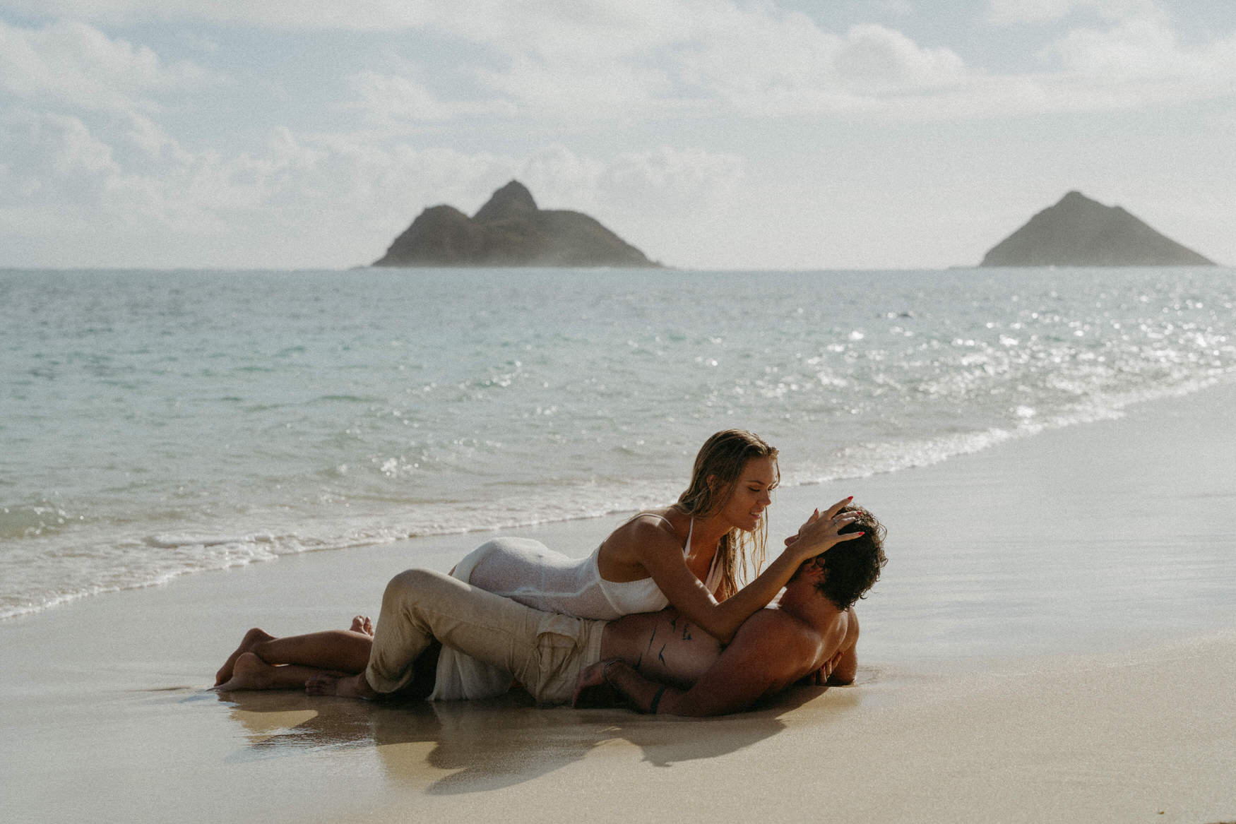 A couple in the sand during their engagement session on Oahu.