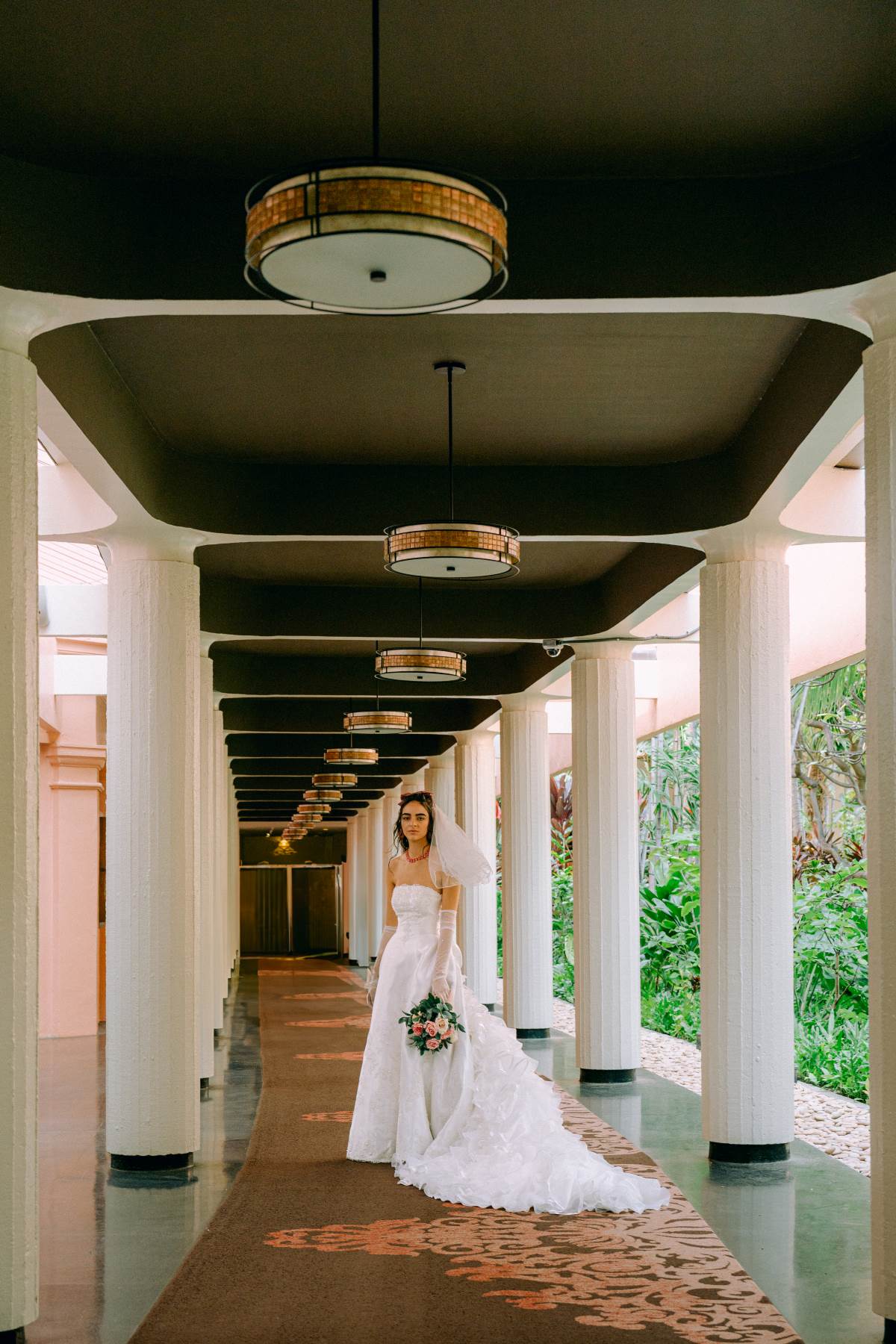 Bride walking through a luxurious hotel hallway in her wedding gown, creating a timeless moment in Wedding Photography on Oahu.