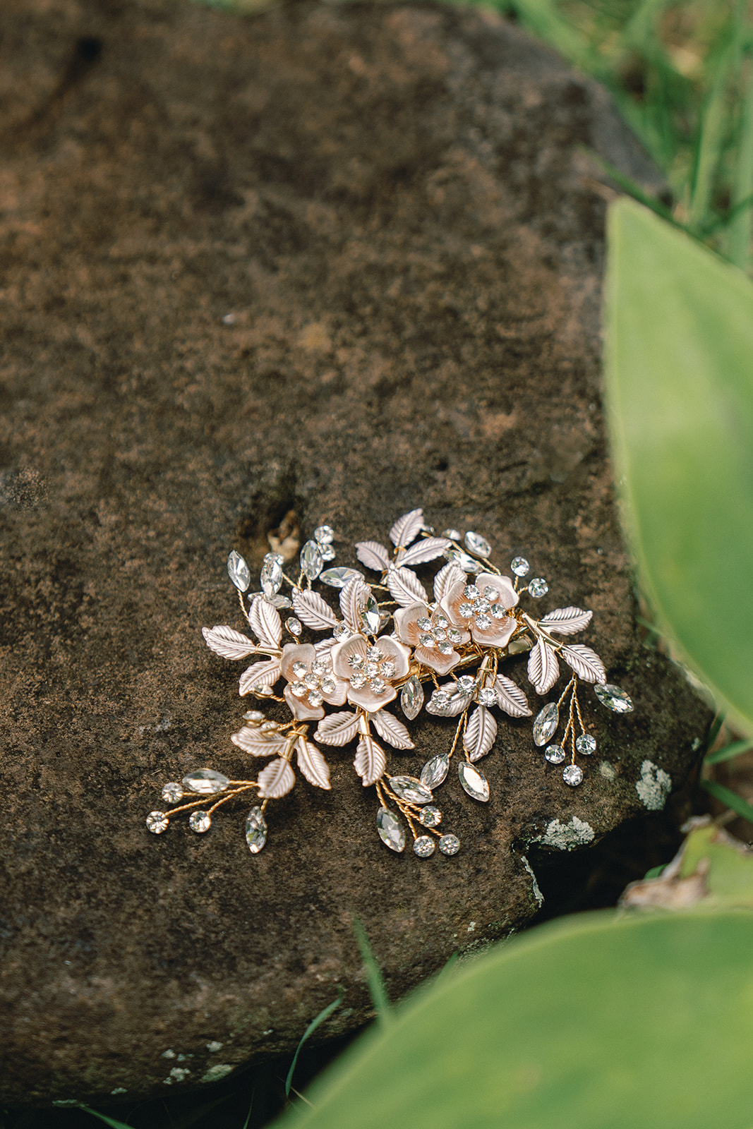 A pair of decorative hairpins with intricate flower designs, resting on a stone surface.
