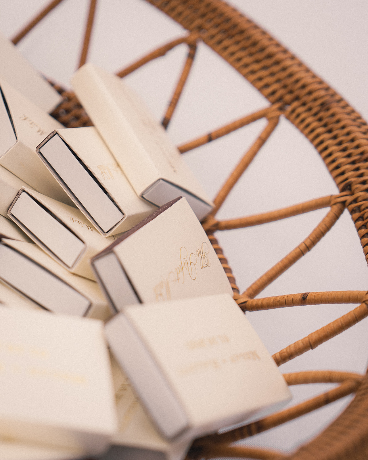 A woven basket filled with personalized wedding matchboxes, elegantly designed in neutral tones.