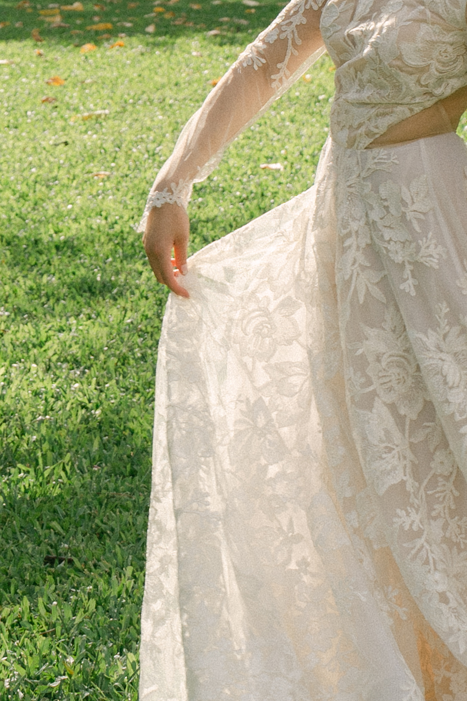 A delicate close-up of a bride’s lace dress catching the wind, bathed in soft sunlight.