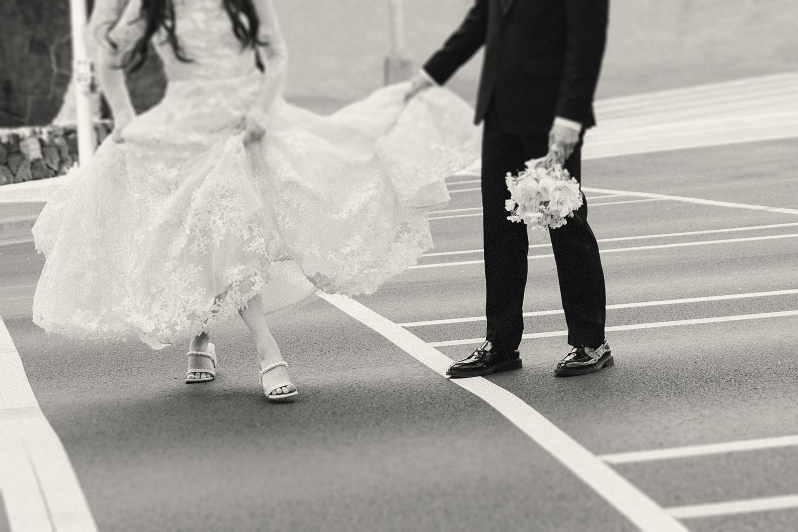 A movement-filled shot of the couple dancing across a parking lot, her lace gown flowing.