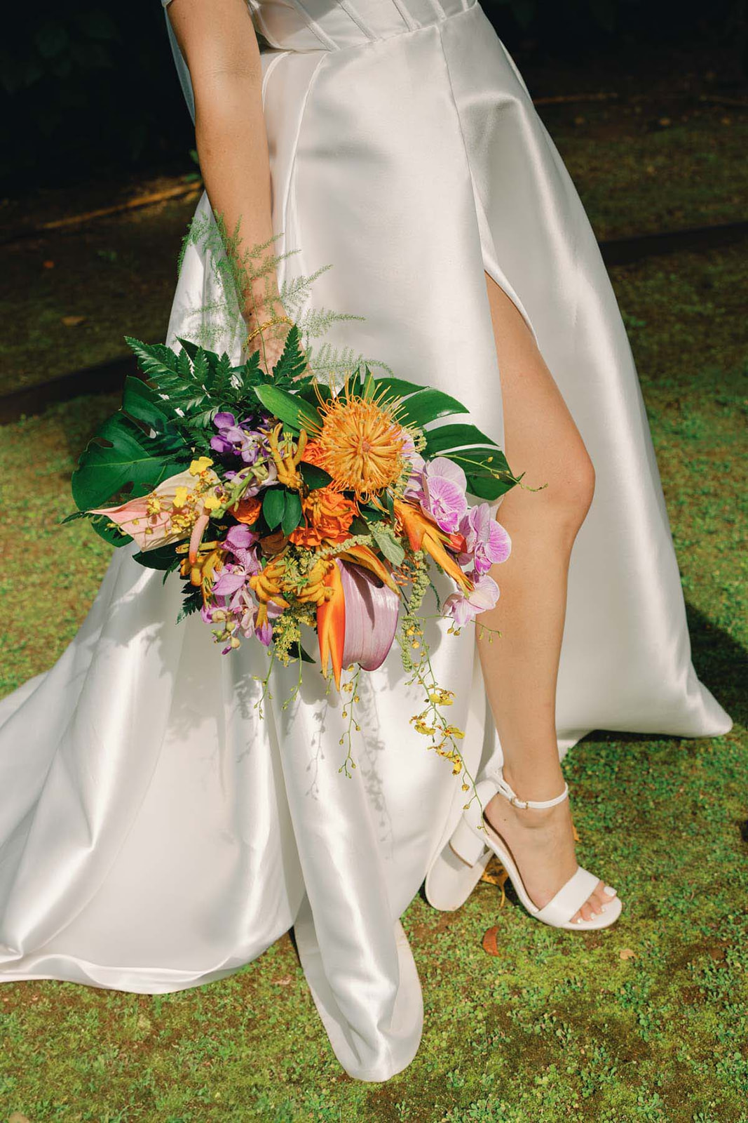 Bride wearing a satin gown and holding a vibrant tropical bouquet, captured in Wedding Photography on Oahu.