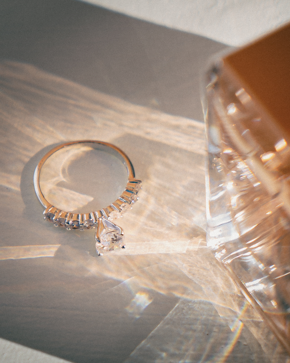 A diamond engagement ring displayed with natural light casting beautiful reflections and shadows on the surface.