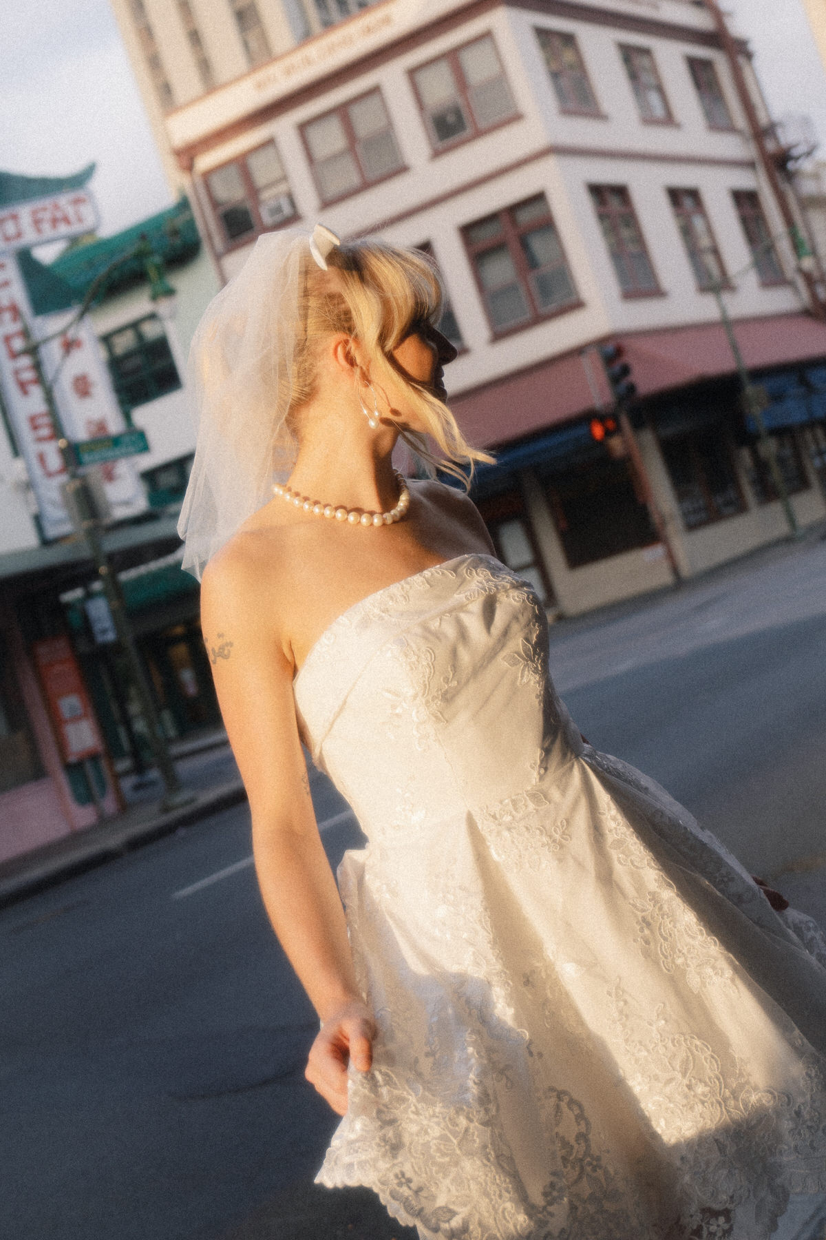 Bride in a strapless wedding dress walking through an urban street, captured with a soft, vintage aesthetic in Bridal Photography in Hawaii.