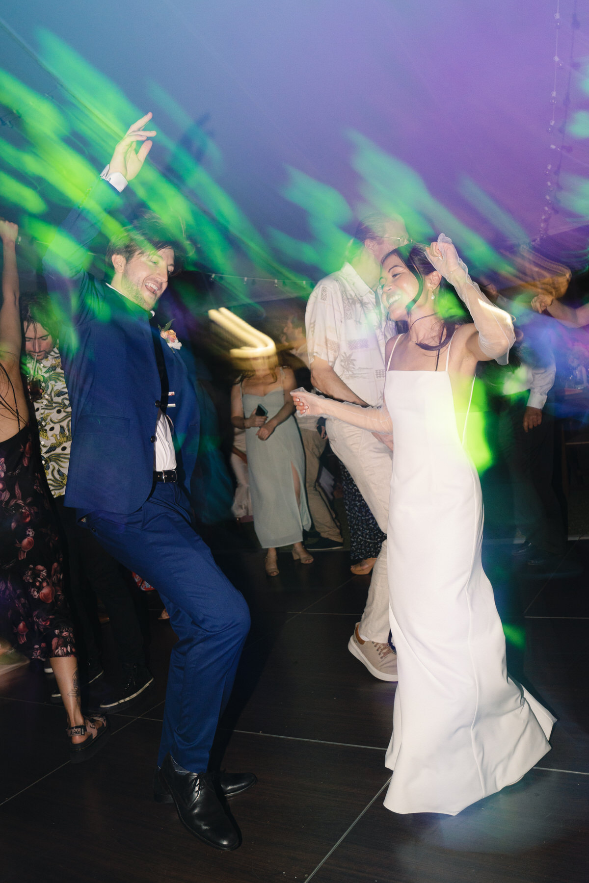 The bride and groom break it down on the dance floor under colorful party lights—epic party vibes from La Pietra Wedding: A Guide for Modern Couples.