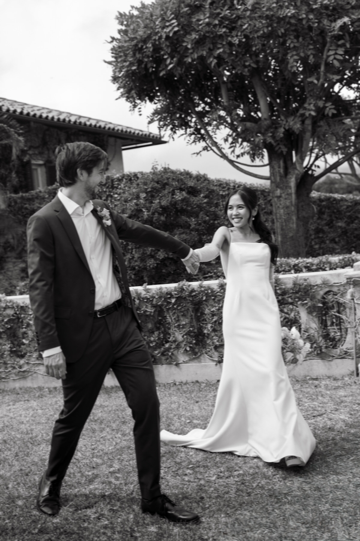 A black-and-white photo of the couple walking through a garden, smiling at each other—timeless romance in La Pietra Wedding: A Guide for Modern Couples.
