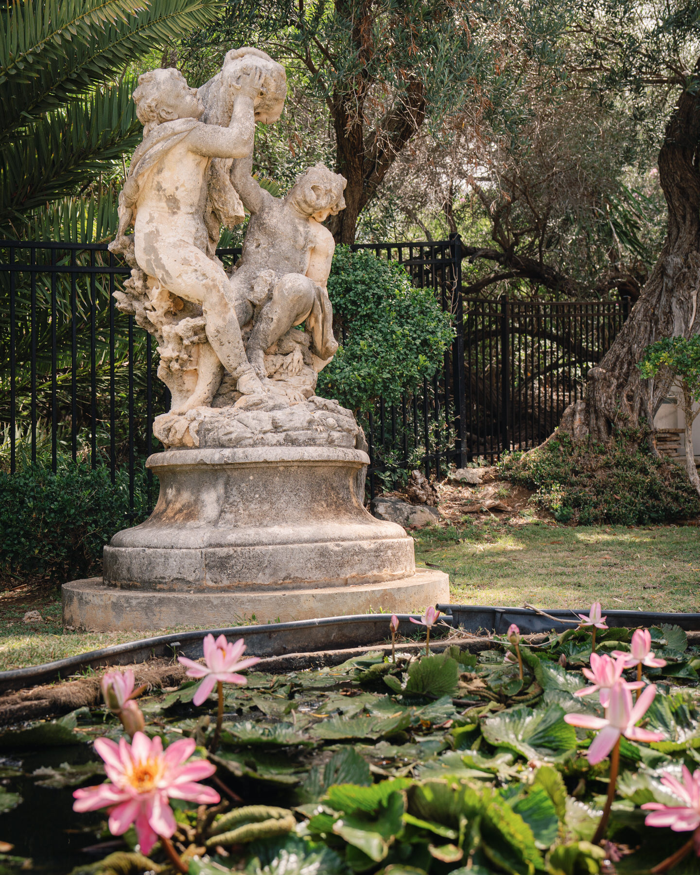A classical stone statue surrounded by blooming pink water lilies in a serene garden setting at La Pietra—highlighting timeless charm in La Pietra Wedding: A Guide for Modern Couples.