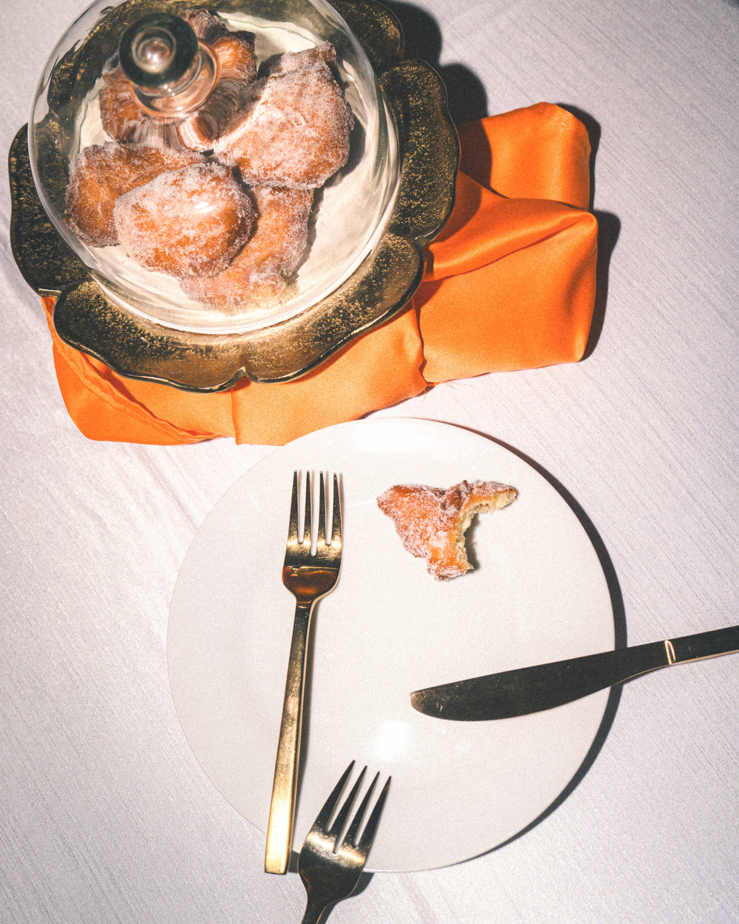 A vintage-inspired dessert display featuring sugar-dusted pastries and golden cutlery on white linen—sweet treats featured in La Pietra Wedding: A Guide for Modern Couples.