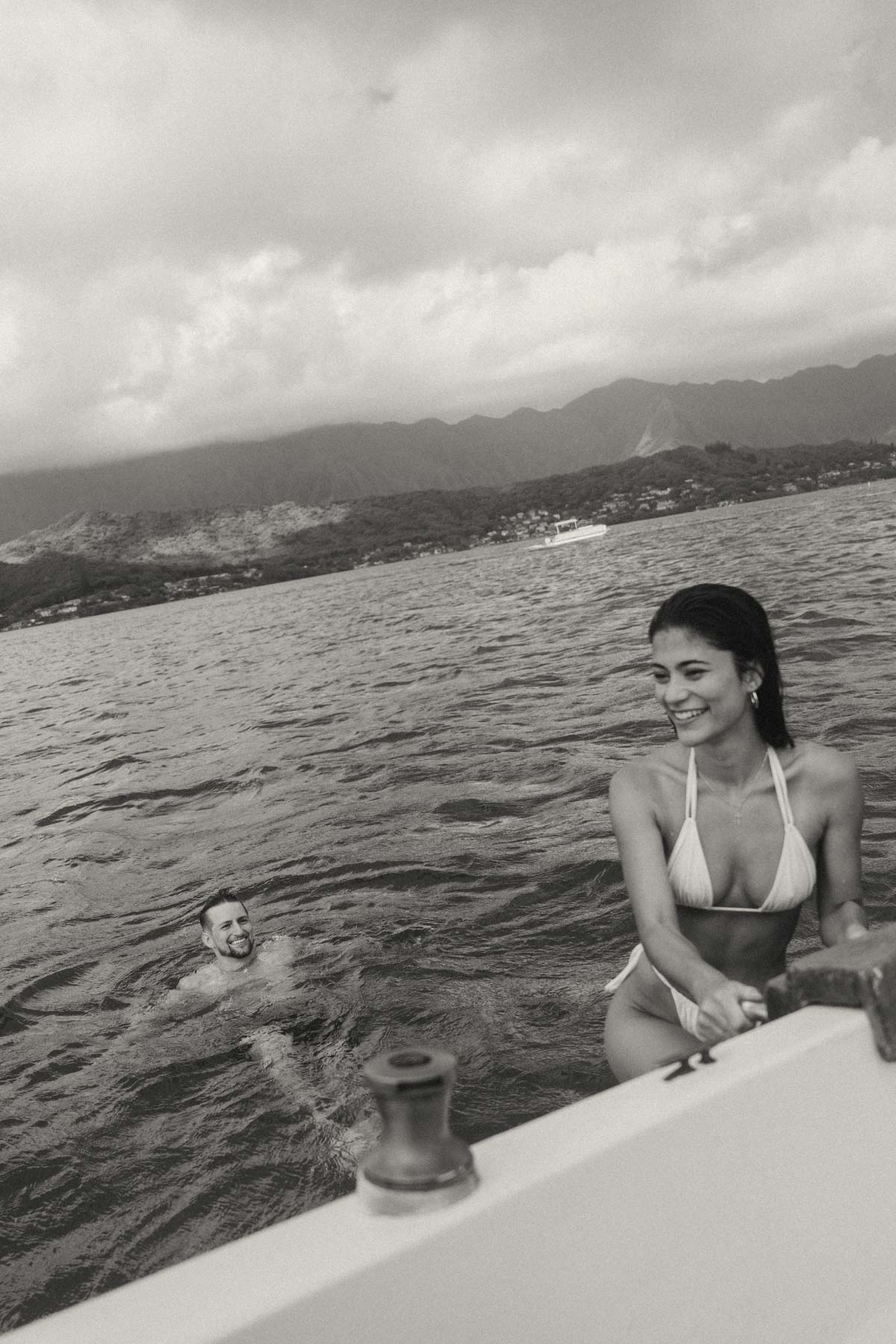 The couple enjoys a quiet moment on a boat as they laugh and gaze at each other. The scene captures the romantic atmosphere, perfect for a Complete Photography Guide in Kaneohe.
