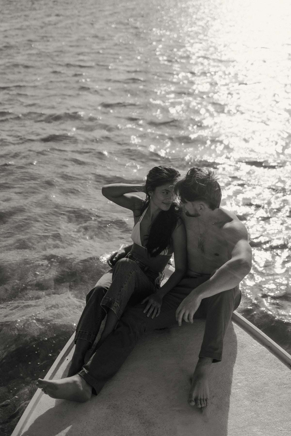 A black-and-white image of a couple sitting on a boat, gazing lovingly at each other. The calm ocean and soft lighting capture a serene moment, perfect for a Complete Photography Guide in Kaneohe.