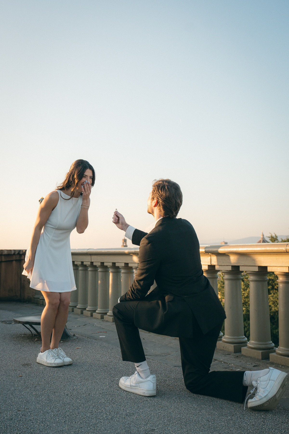 Couple sharing a beautiful and spontaneous moment of joy after the proposal on a rooftop, captured in Marriage Proposal Photo Session in Oahu.