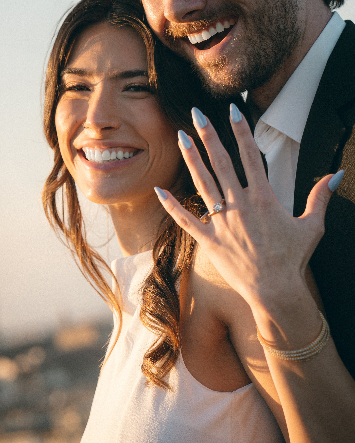 Happy couple showing off their engagement rings and smiling together, captured during a marriage proposal photo session in Oahu.