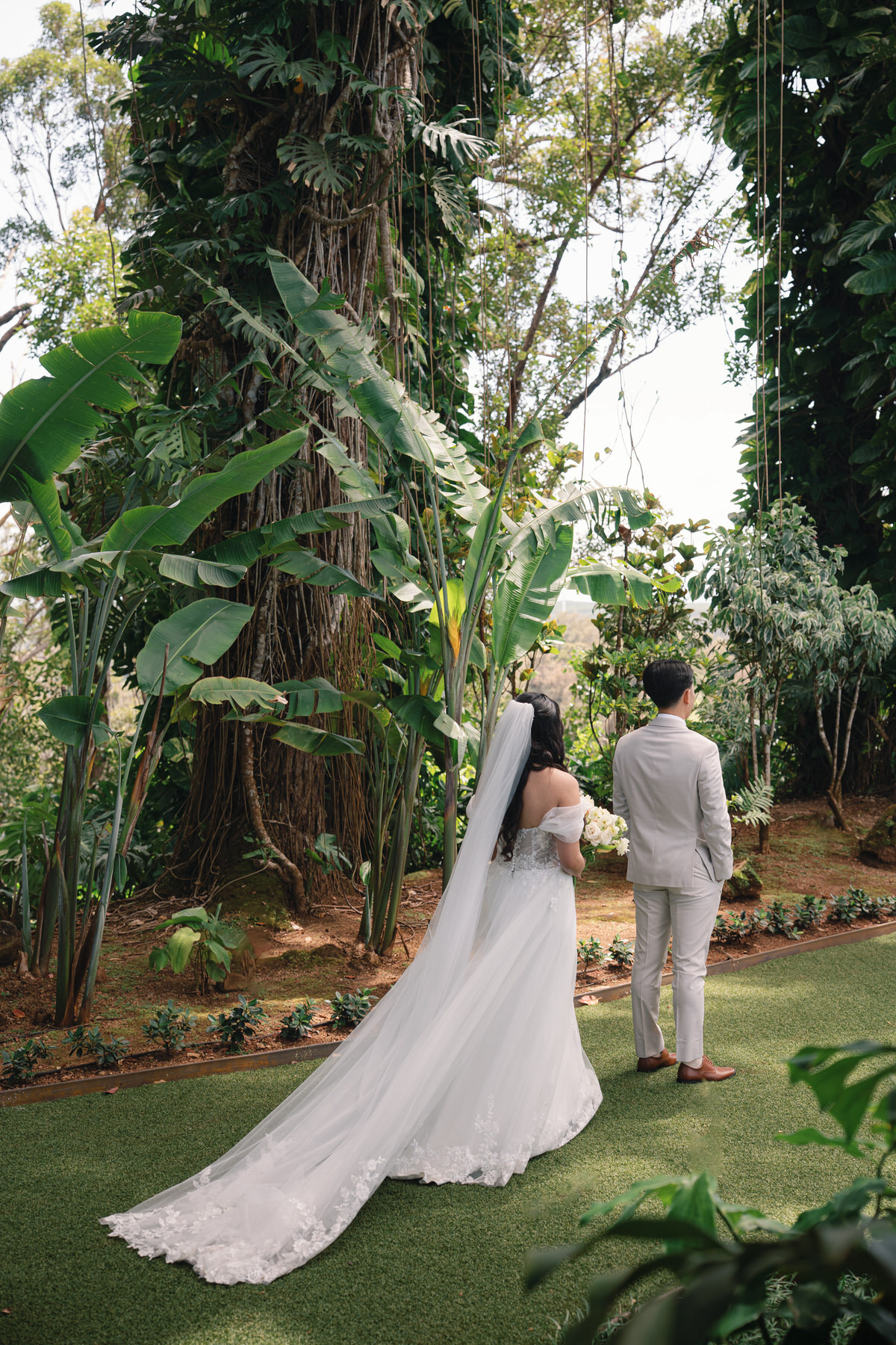 Bride walking hand in hand with her groom in a lush garden, capturing a tender moment in Wedding Photography on Oahu.