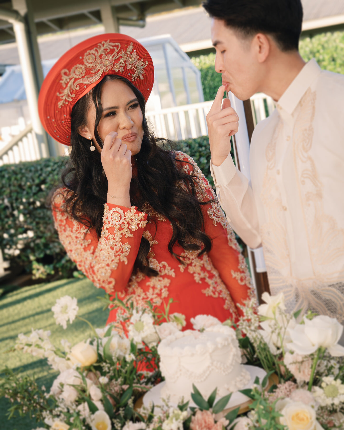 Bride and groom sharing a sweet moment as they feed each other cake, surrounded by lush flowers, captured in Wedding Photography on Oahu
