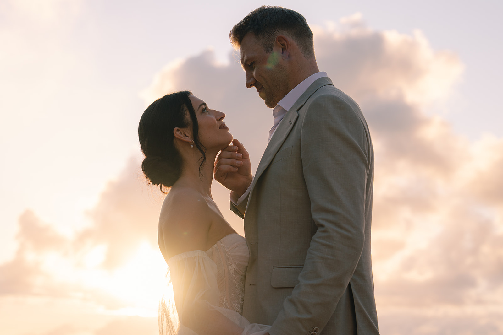 Couple facing each other at sunset on rocky coast during engagement shoot – Top Questions to Ask Your Wedding Photographer Before Booking
