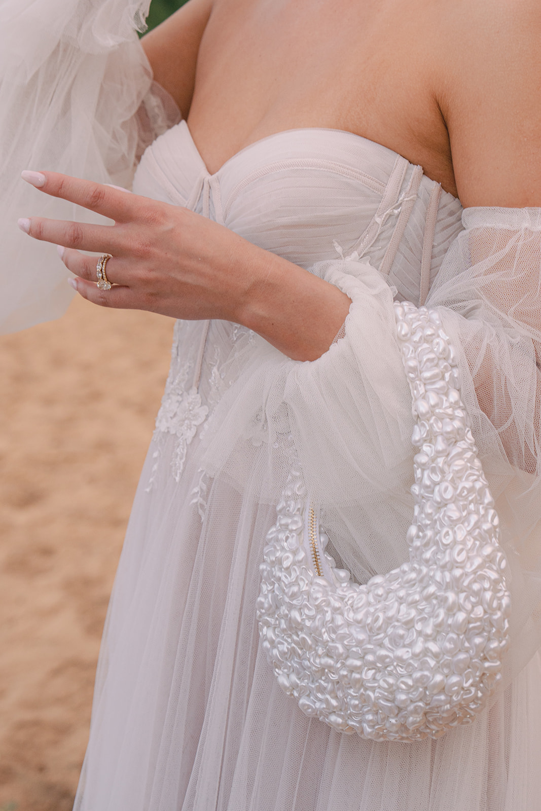 Bride in corset gown holding sequin clutch on Oahu shoreline – Top Questions to Ask Your Wedding Photographer Before Booking