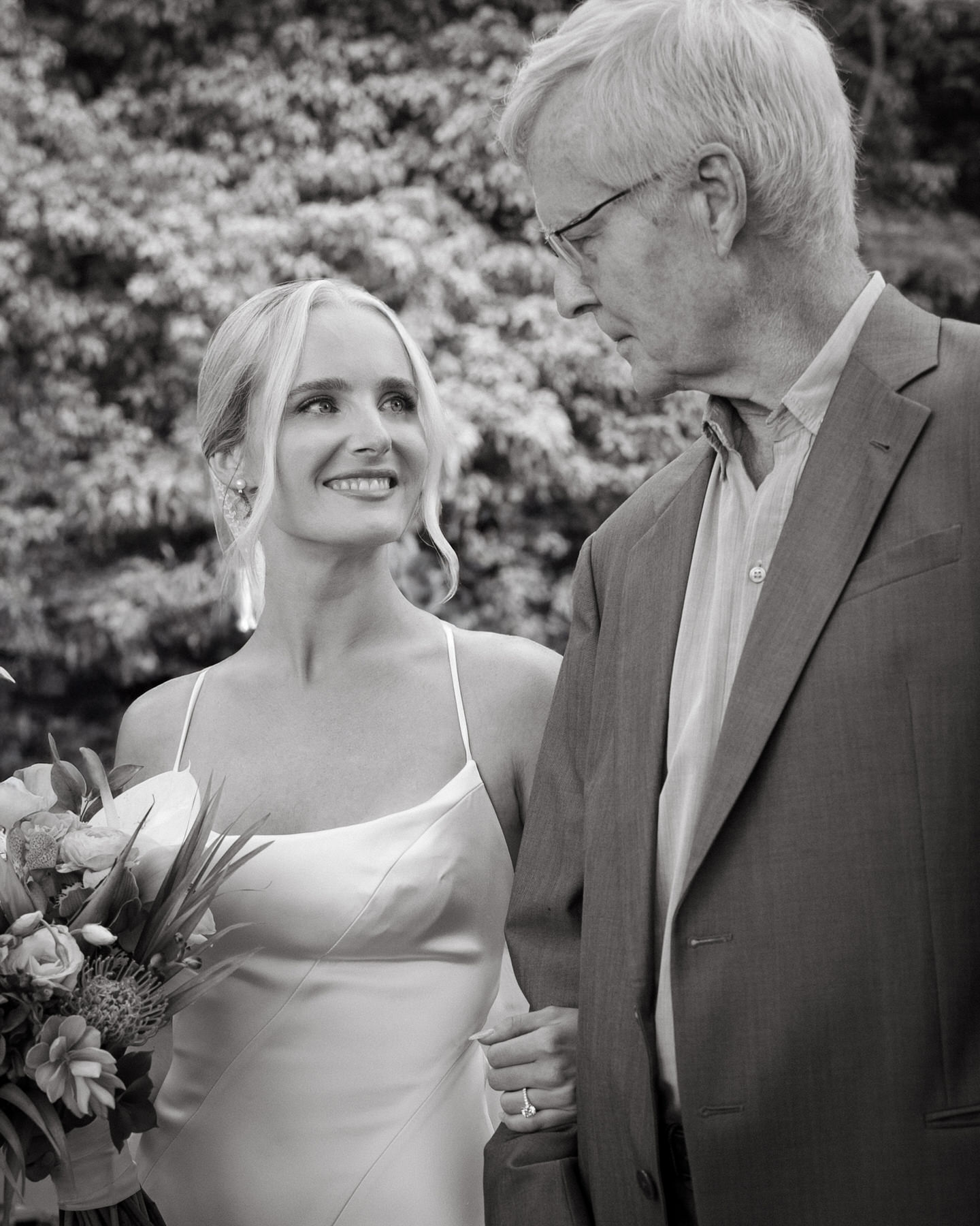 Father and bride sharing a meaningful moment before the ceremony at Kualoa Ranch, Paliku Gardens, with a lush green backdrop.