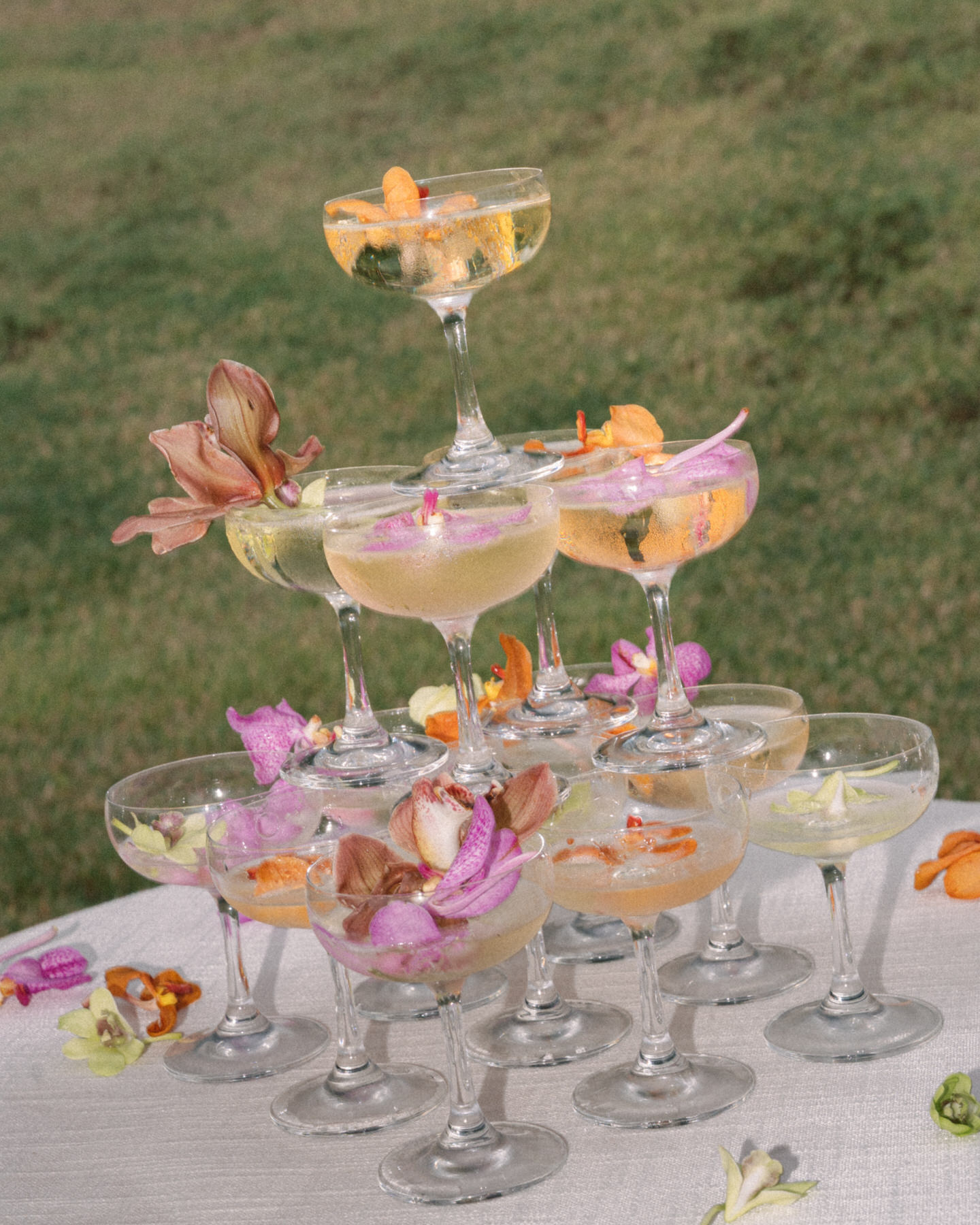 Stacked champagne glasses at a wedding reception, surrounded by flowers, at Kualoa Ranch, Paliku Gardens, Oah