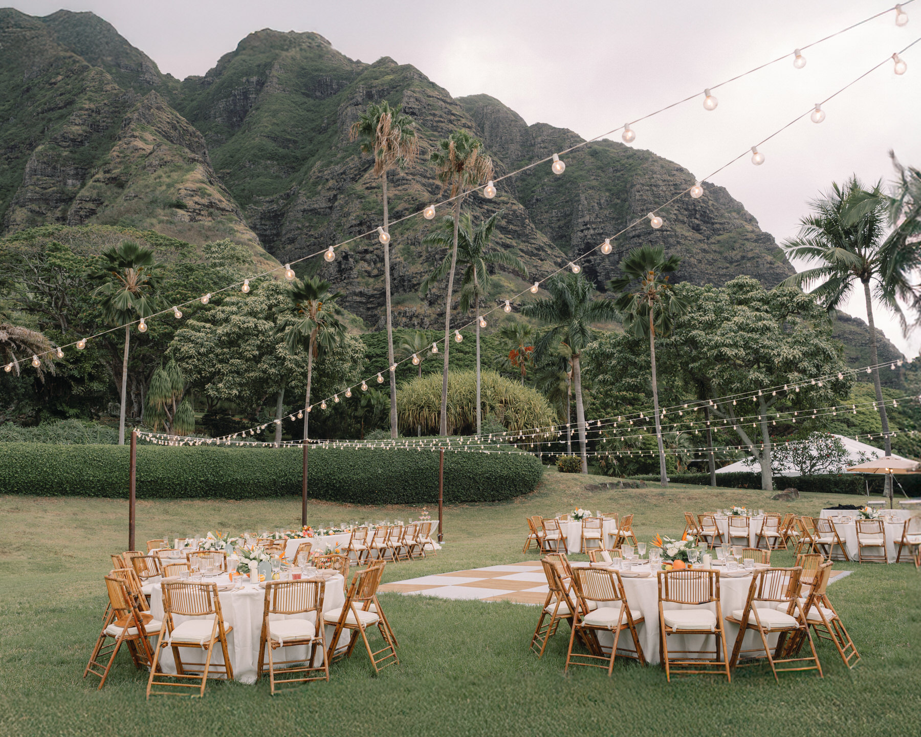 Elegant wedding reception setup with twinkling lights and floral centerpieces at Kualoa Ranch, Paliku Gardens, Oahu.
