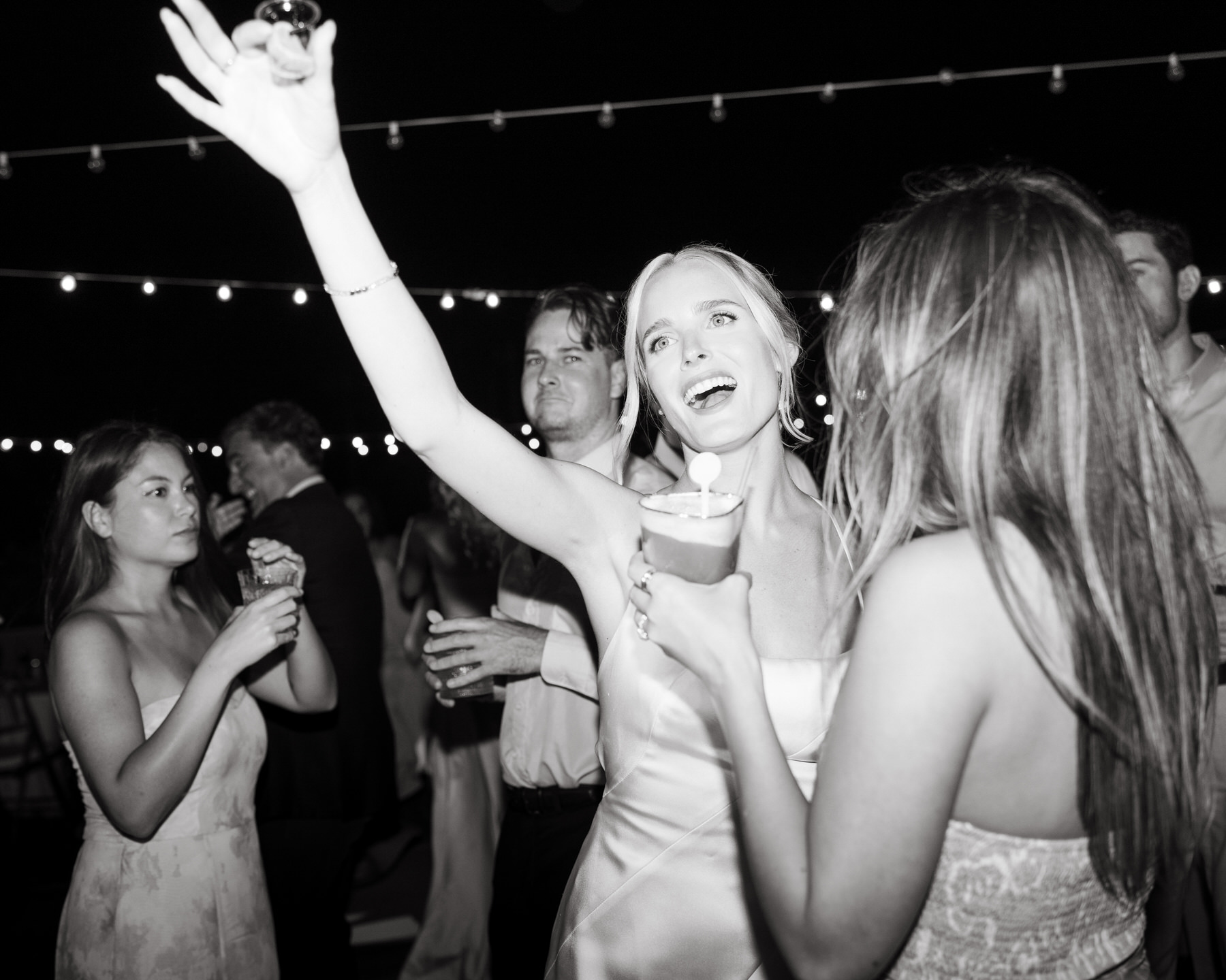 Bride celebrating with friends on the dance floor under string lights at Kualoa Ranch, Paliku Gardens in Oahu