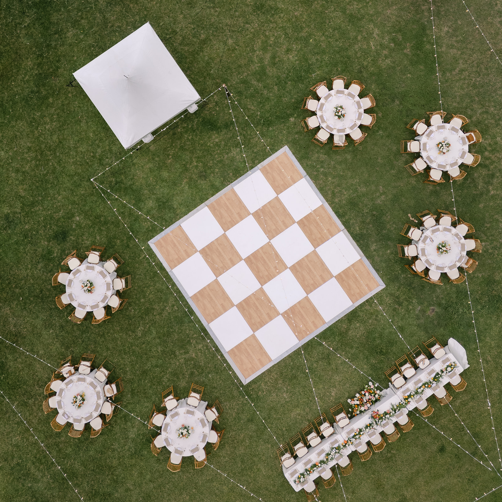 Aerial view of the wedding reception setup at Kualoa Ranch, Paliku Gardens, with a checkered dance floor and elegant tables.