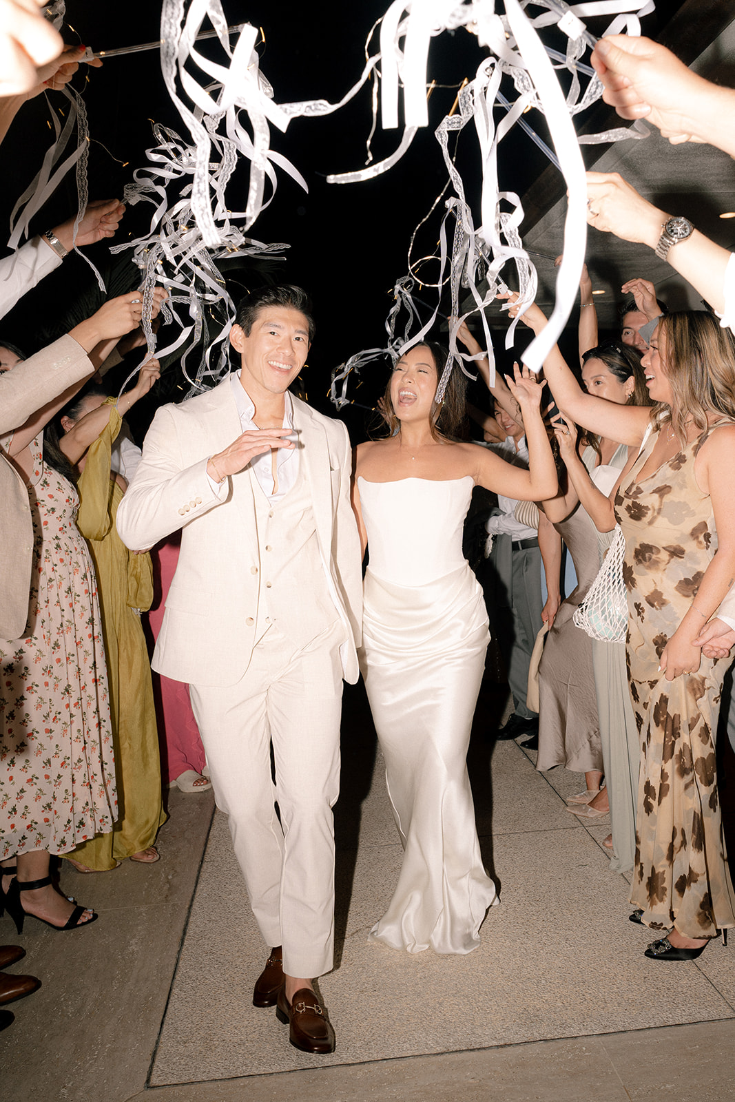 Brenda and Jason's chic wedding exit at Halekulani Hotel in Waikiki, Hawaii, surrounded by ribbon wands.