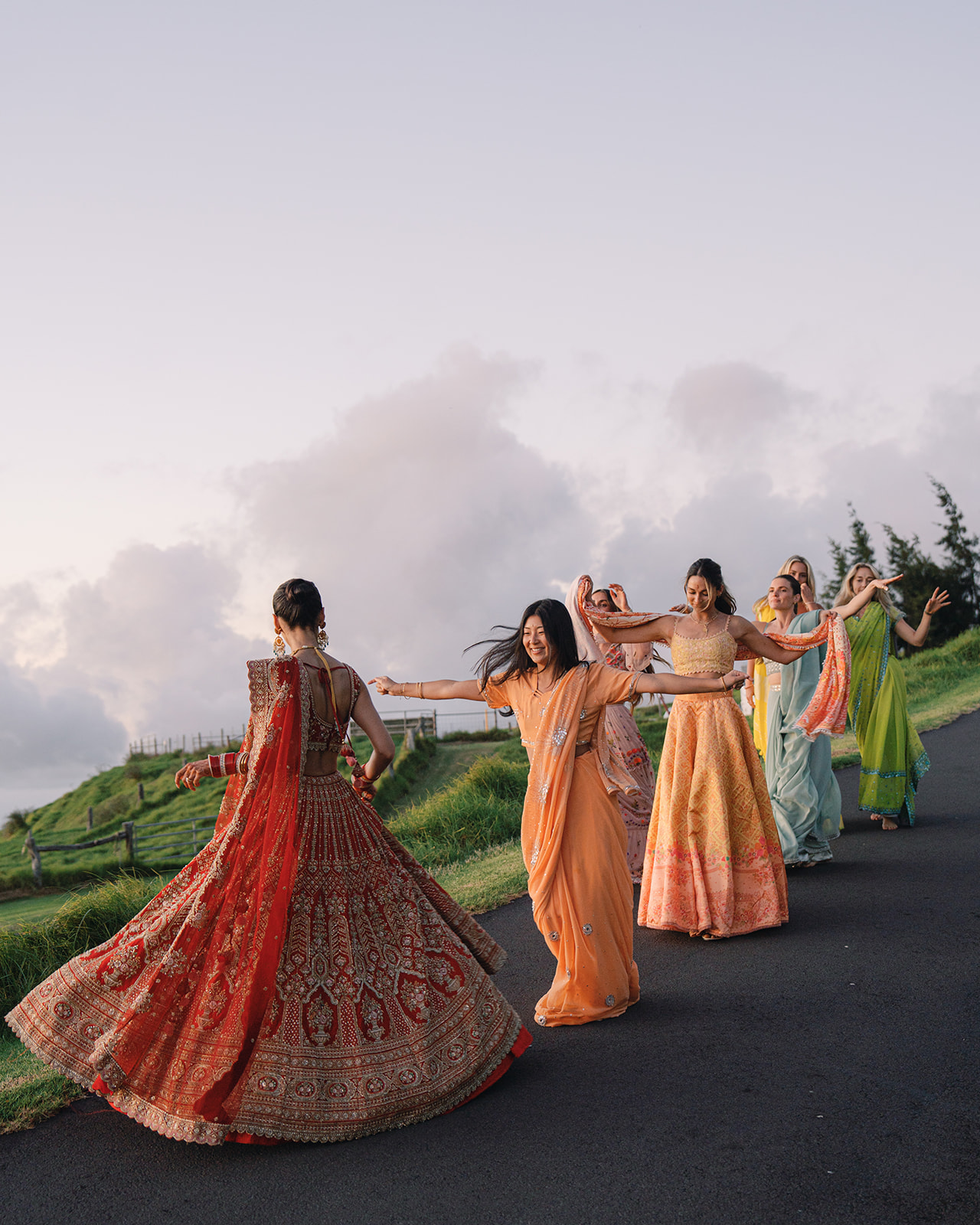 Bridal party in vibrant traditional attire, captured in timeless modern wedding photography, enjoying a joyful moment during an outdoor celebration.