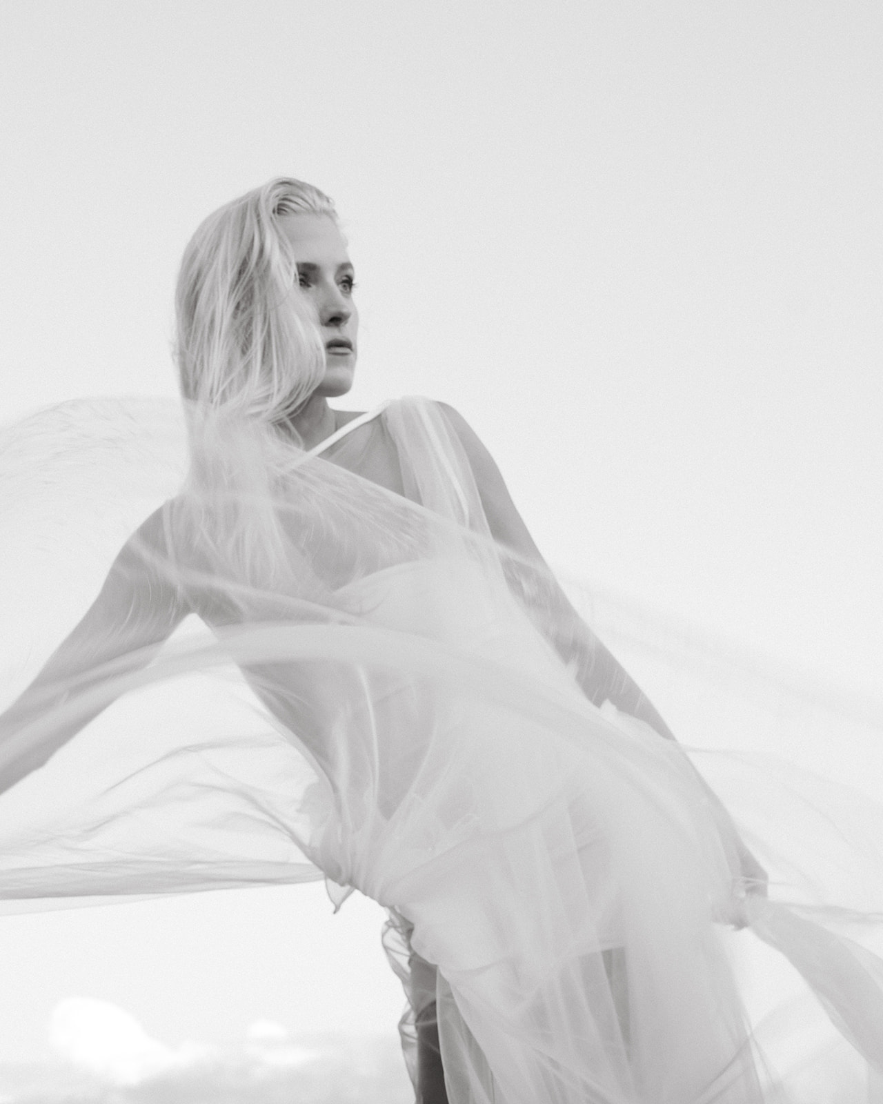 A bride in a flowing white gown, captured in an editorial wedding style at the beach, achieving a timeless yet contemporary look in her wedding photos.