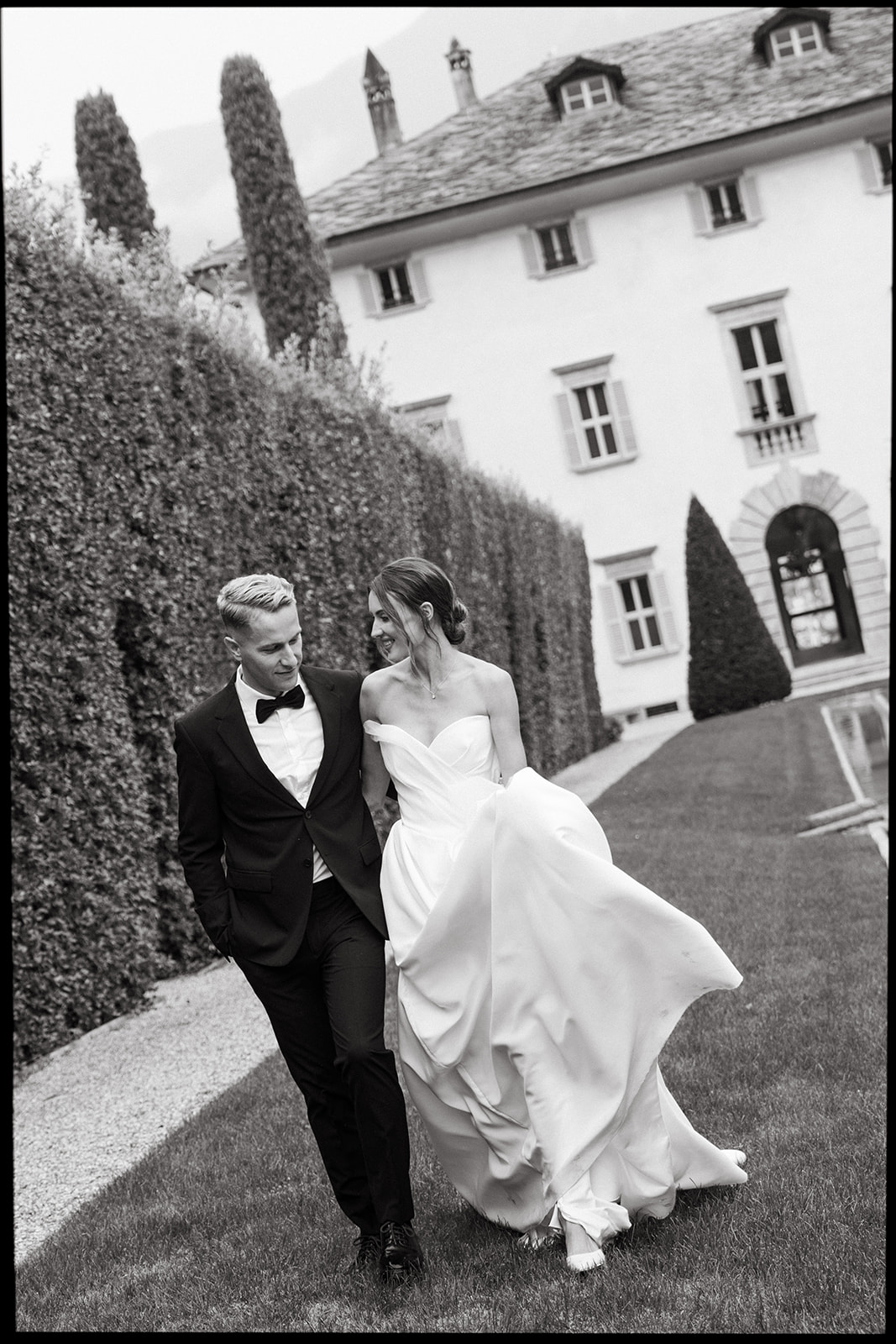 A couple walks hand-in-hand through the gardens of Villa Balbiano, Lake Como, in a relaxed editorial wedding photography style. The timeless moment captures artful elegance and natural beauty.