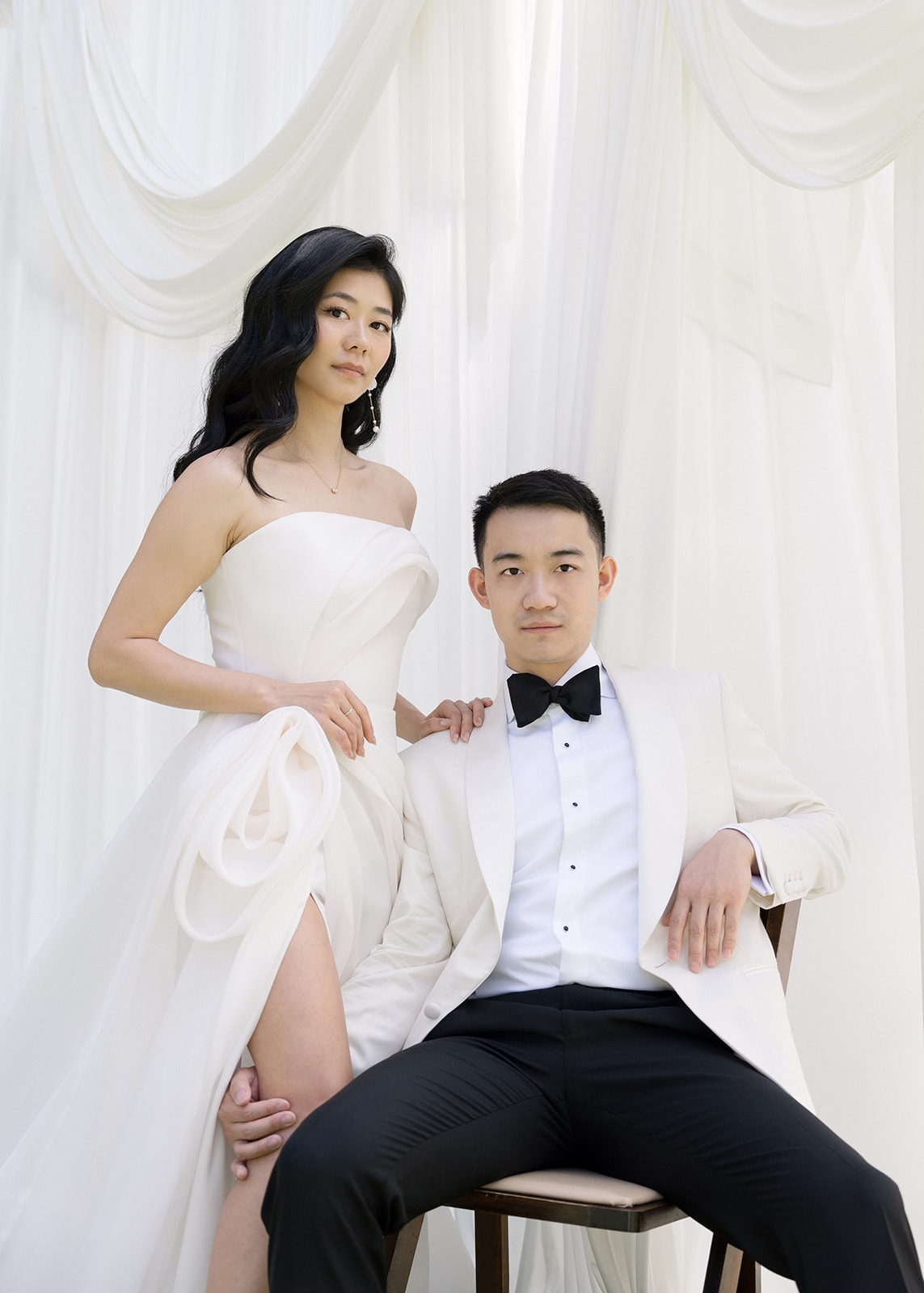 Elegant couple in wedding attire, with the bride in a strapless gown and the groom in a white tuxedo, captured at Kona Beach House for a tropical Big Island wedding.