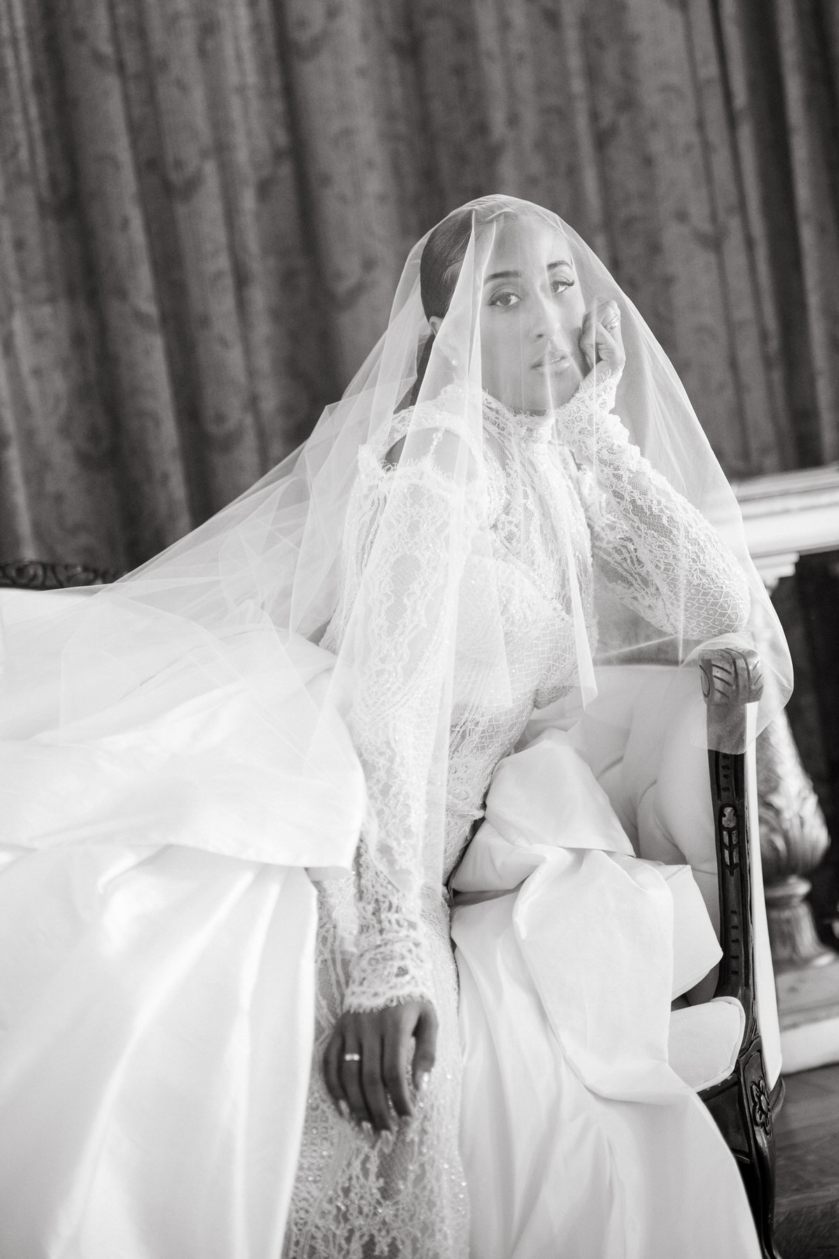 Bride sitting gracefully on a chair, gazing through her veil in a moment of elegance at her brunch wedding at Ochre Court Newport.