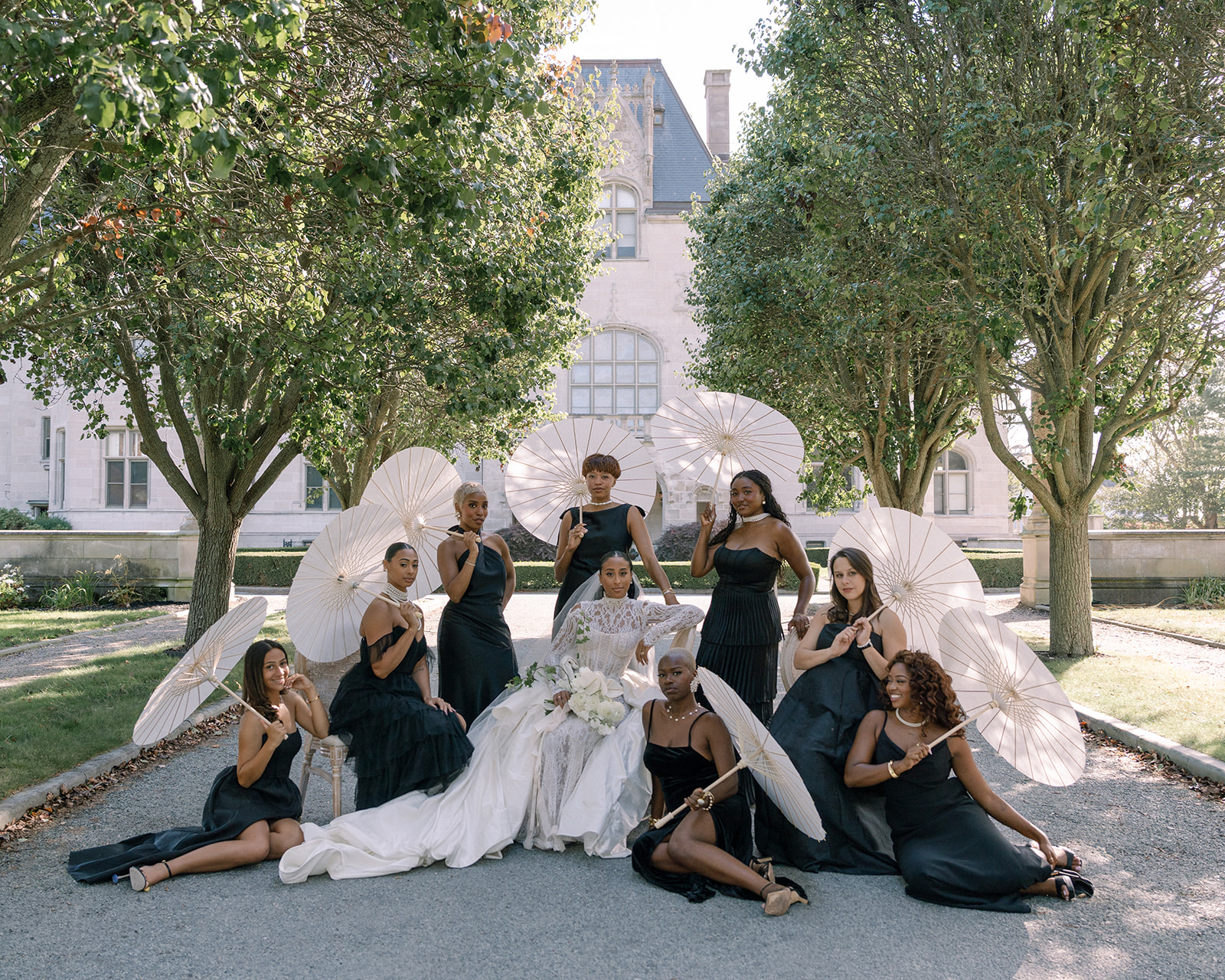 Bride with her bridal party, striking a dramatic pose with parasols, captured during the Brunch Wedding at Ochre Court Newport.
