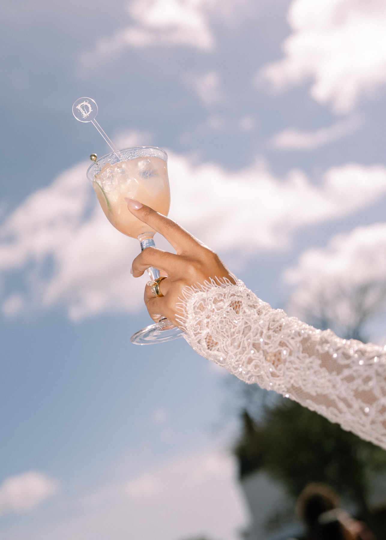 Bride raising a glass of champagne in celebration during the brunch wedding at Ochre Court Newport, with a beautiful blue sky in the background.